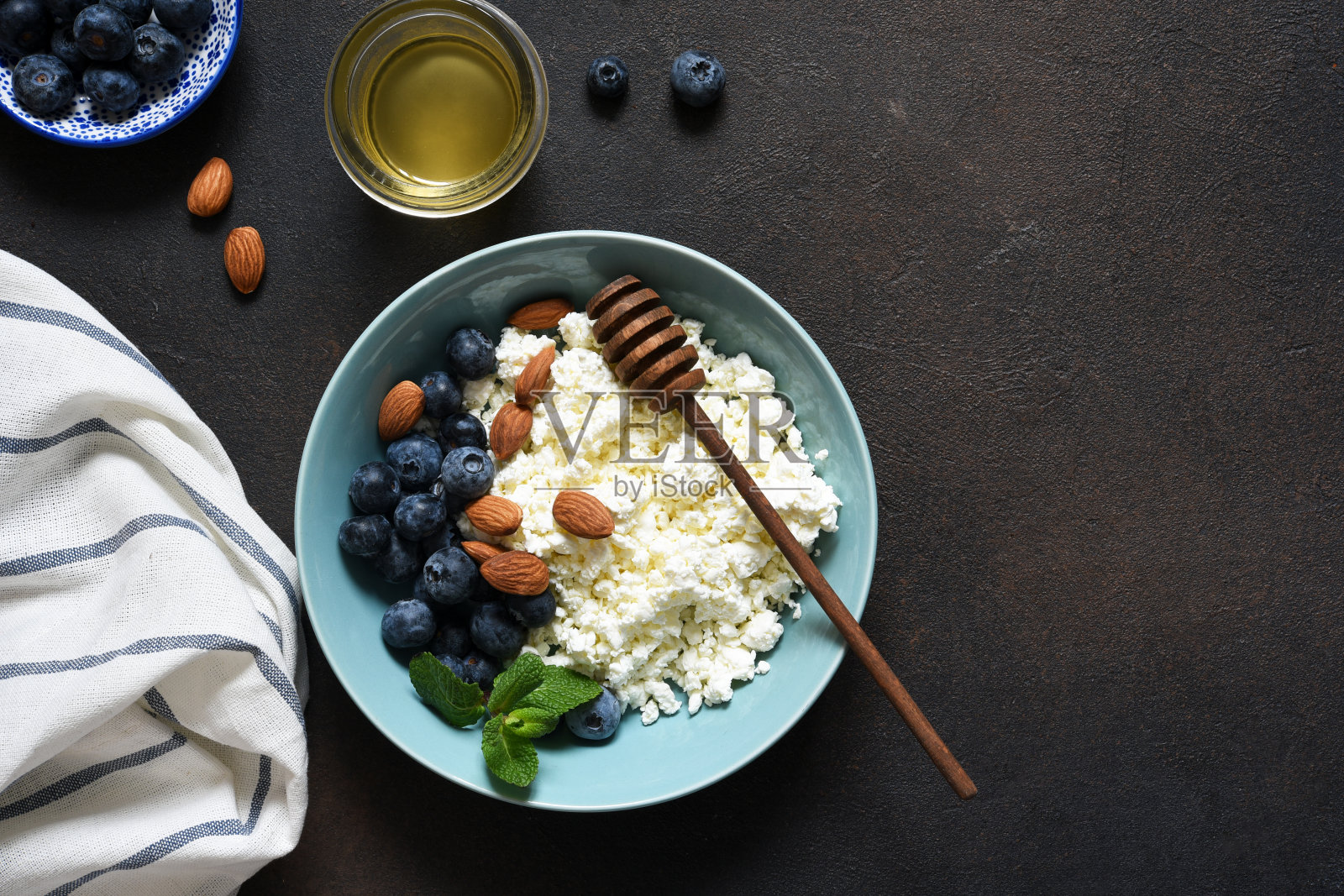 美丽的早餐-白软干酪，浆果和蜂蜜在厨房的桌子上。早上好。照片摄影图片