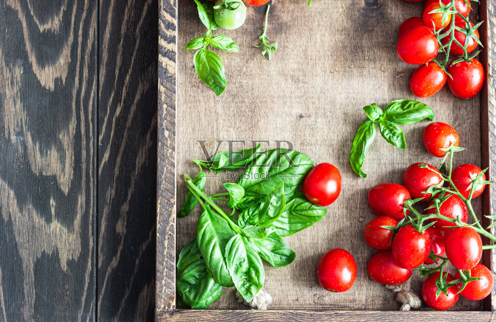 新鲜成熟的圣女果和罗勒木背景。照片摄影图片