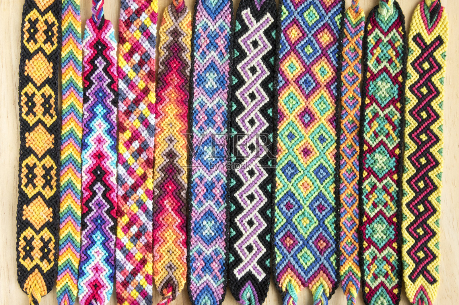一组简单手工自制的友谊天然编织手链，以木制为背景，彩虹色，格子图案照片摄影图片