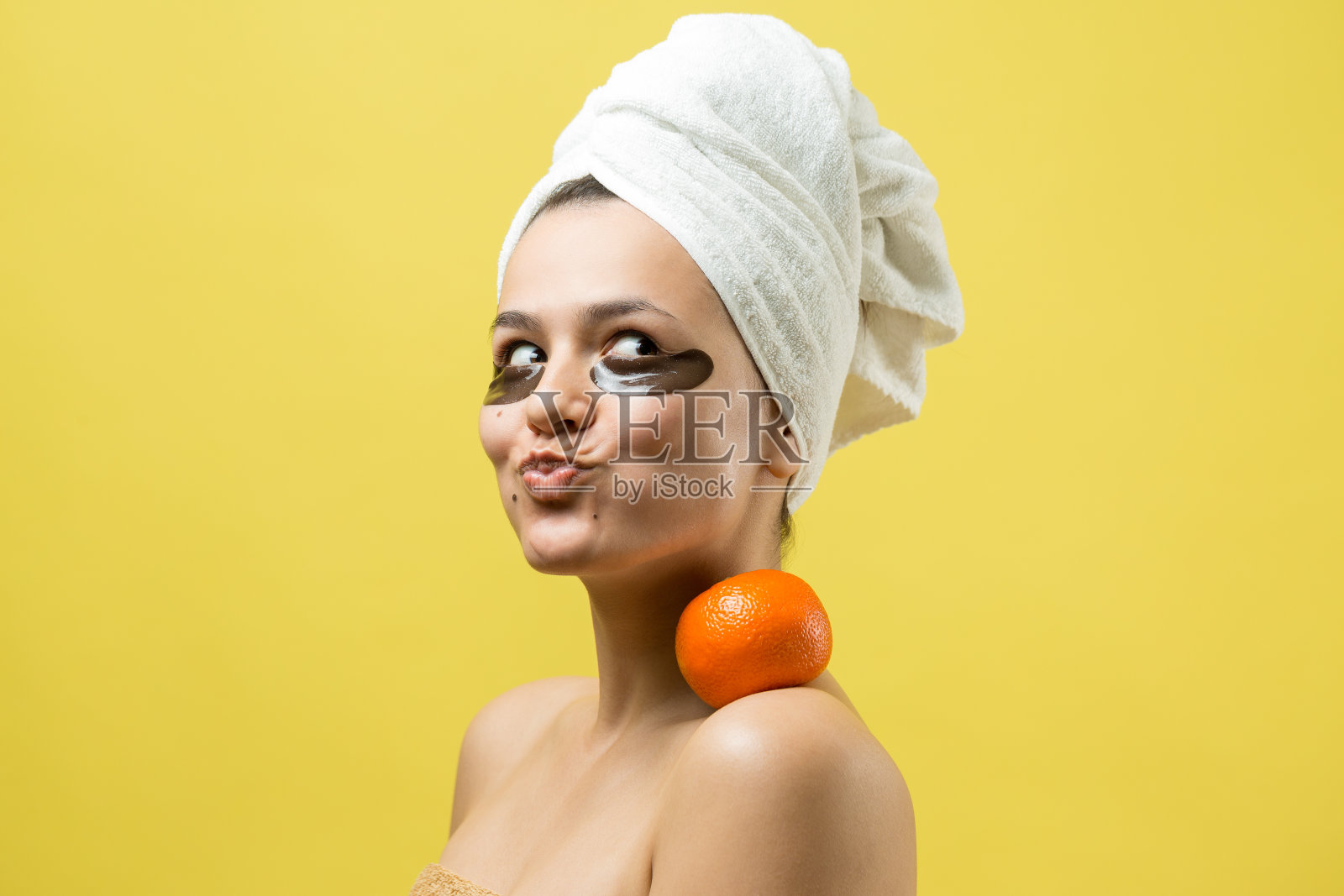 年轻美丽的女孩在一个白色的毛巾在他的头上戴着胶原凝胶眼罩。敷眼罩治疗面部。照片摄影图片