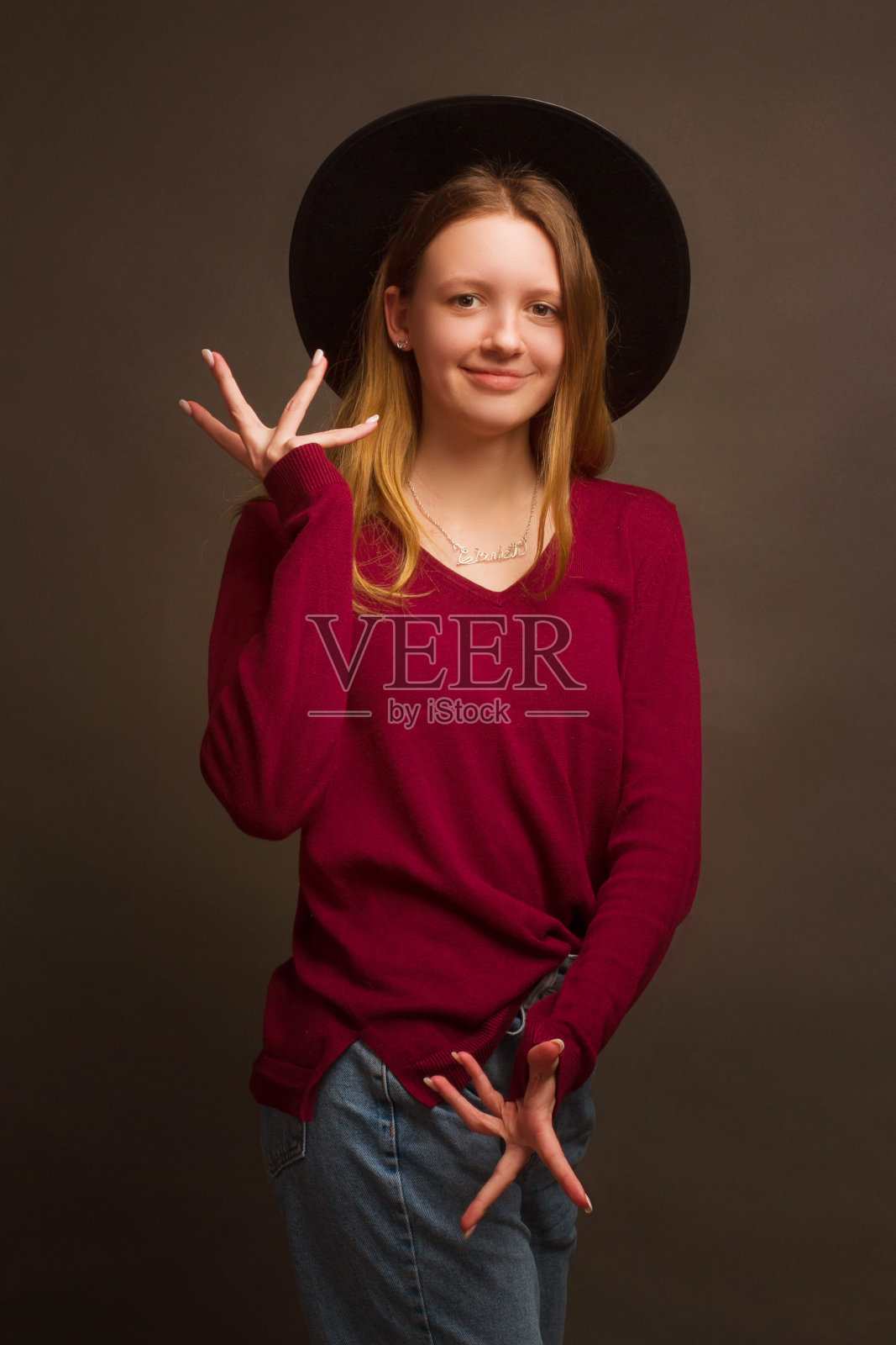 画着金色头发，穿着红色毛衣和蓝色牛仔裤的女孩在工作室的肖像照片摄影图片