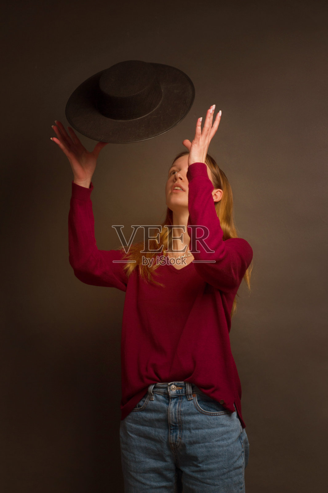 画着金色头发，穿着红色毛衣和蓝色牛仔裤的女孩在工作室的肖像照片摄影图片