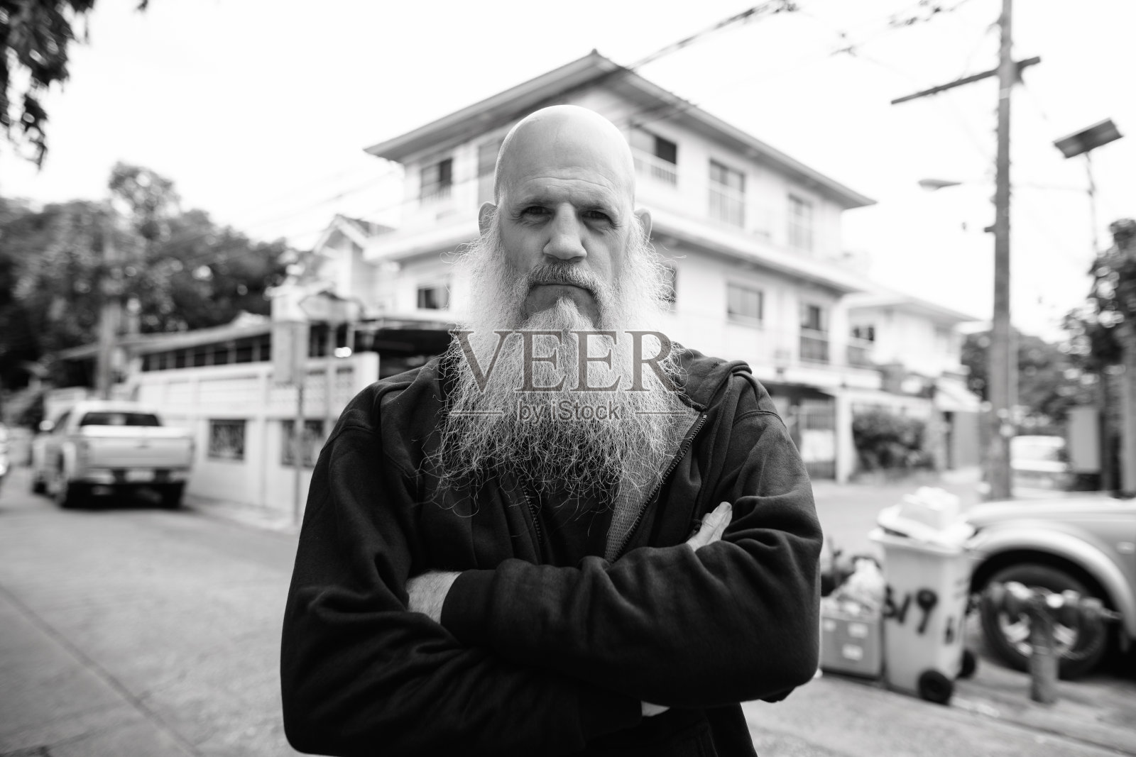 在户外的街道上，满脸胡须的秃顶男人交叉着双臂照片摄影图片