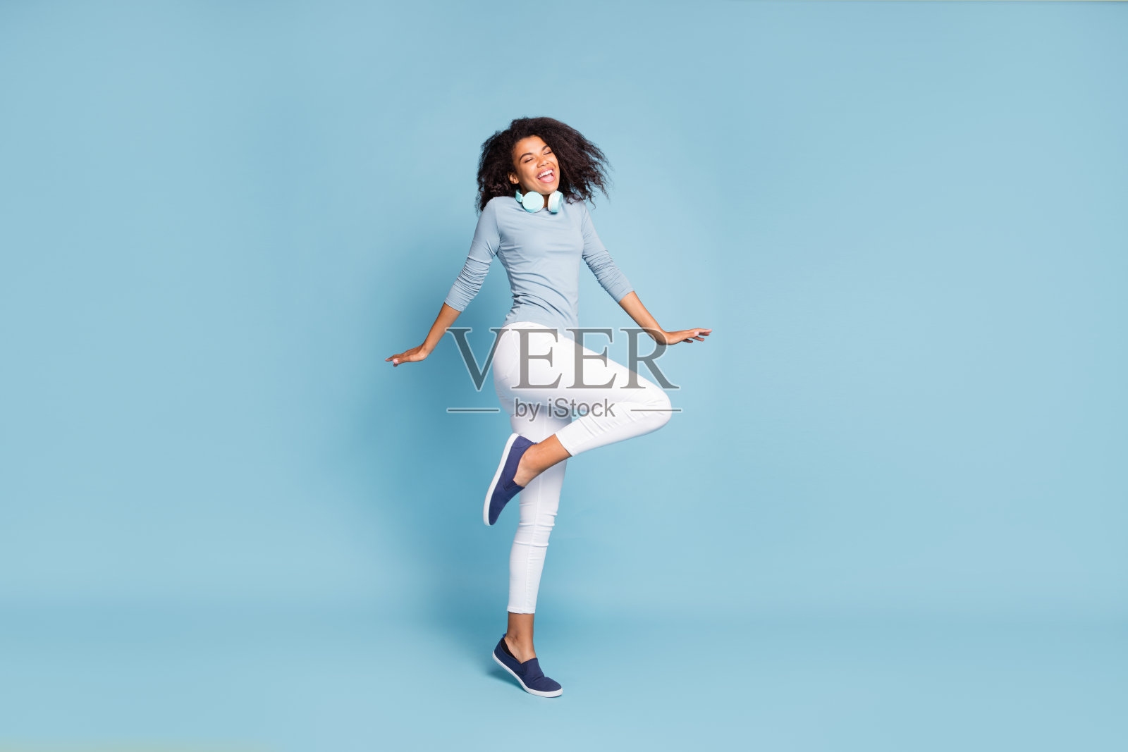 全身尺寸侧面侧面的照片，开朗积极可爱的好女朋友闭上眼睛兴奋地离开了独自在白色裤子孤立的柔和的蓝色背景照片摄影图片