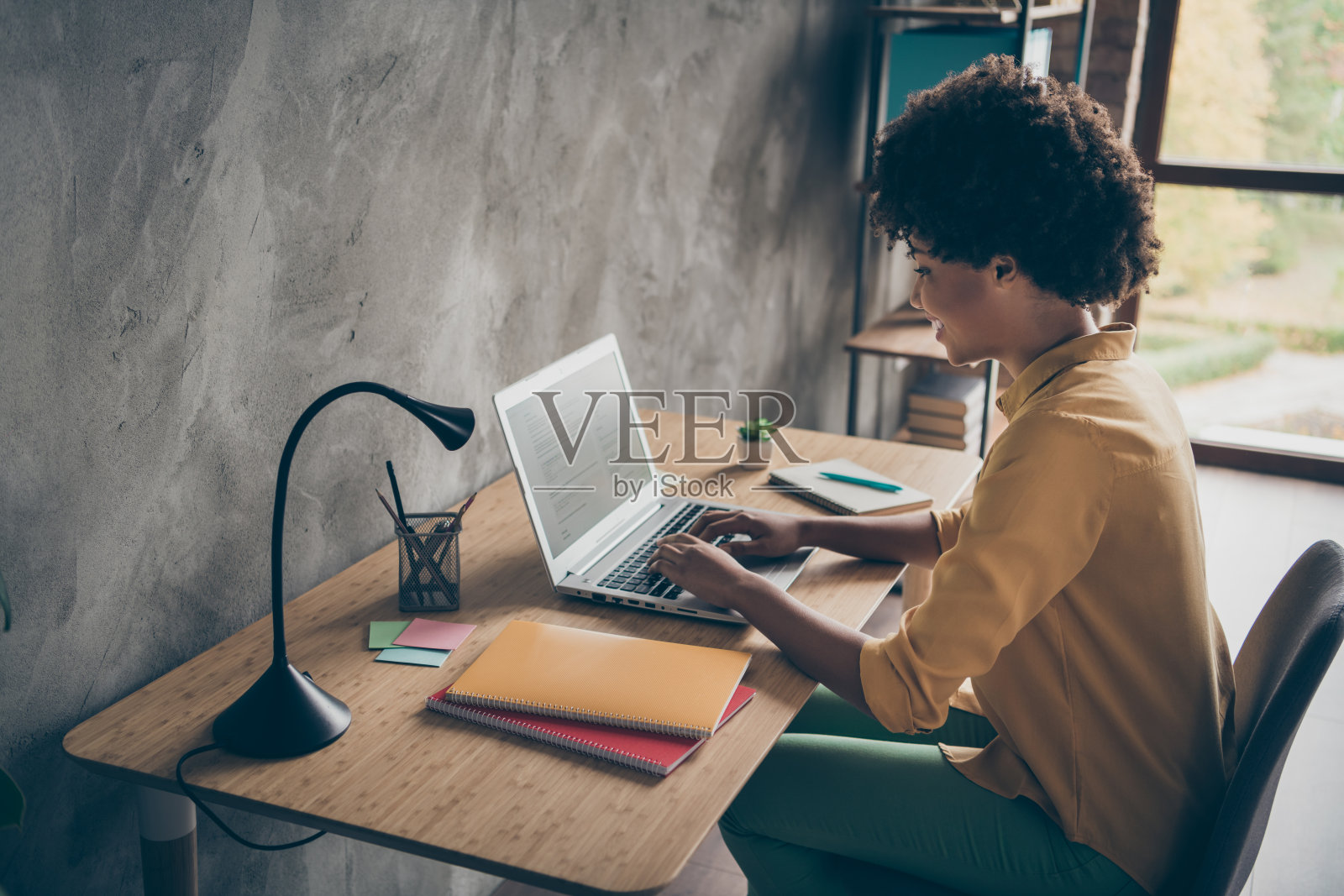 专注的美国黑人女孩smm工作人员使用笔记本电脑阅读启动信息工作演示坐在办公室阁楼工作站的桌子上照片摄影图片