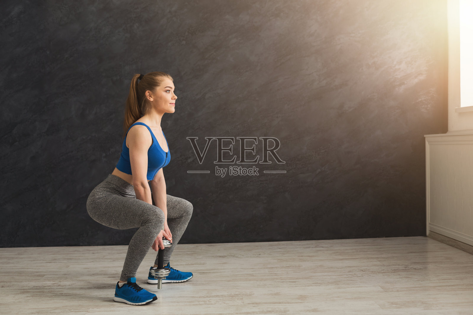 年轻漂亮的女人穿着运动服蹲着照片摄影图片