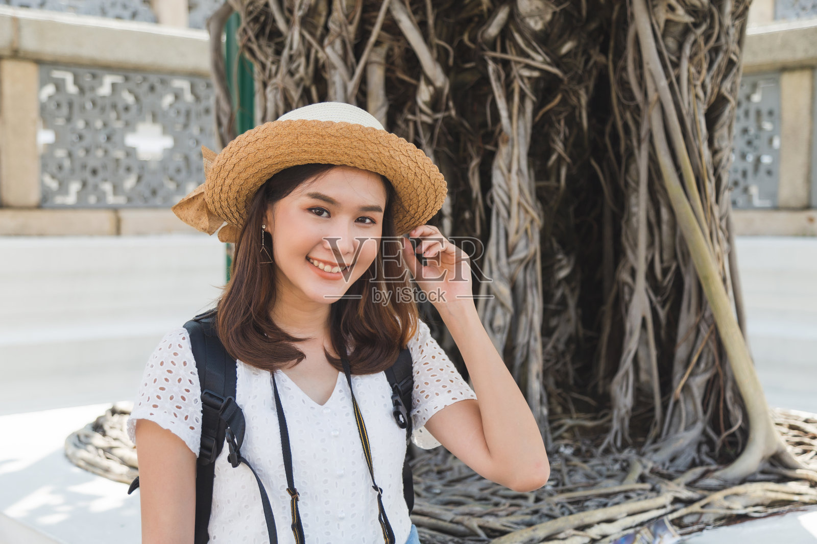 肖像美丽的年轻亚洲妇女穿着白色的裙子站和触摸她的头发在Wat Phra Kaew最喜欢的地方在泰国曼谷。公共区域。照片摄影图片