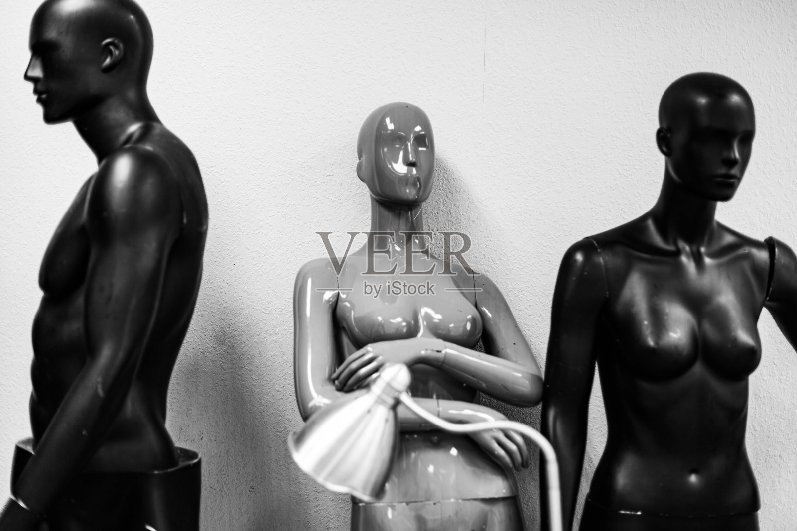 几个假人在一堵明亮的墙后面照看着一盏台灯照片摄影图片