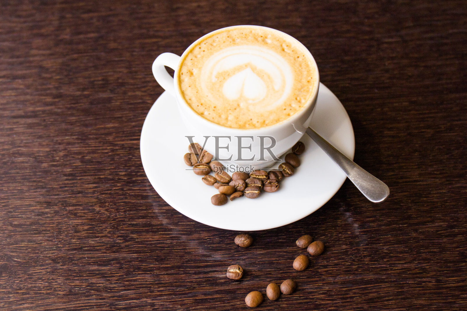 白色杯子里的咖啡豆。在一张棕色的桌子上放着一杯咖啡。照片摄影图片