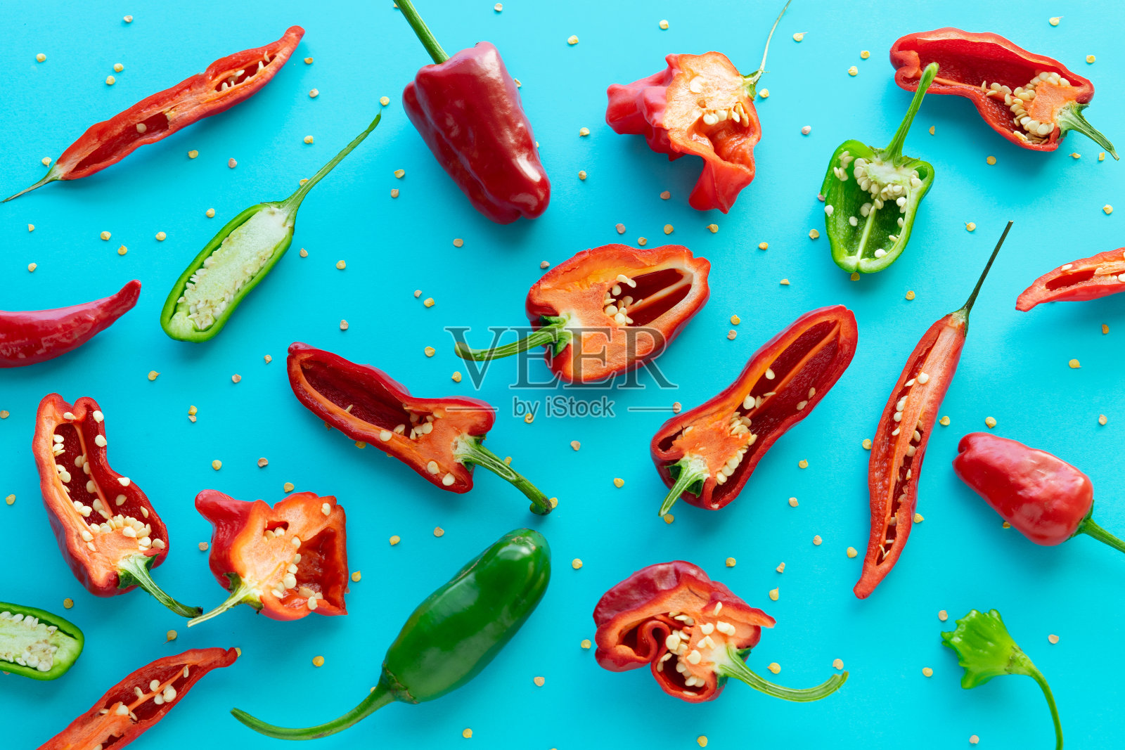 红青椒在蓝色底色上切成两半，平铺。照片摄影图片