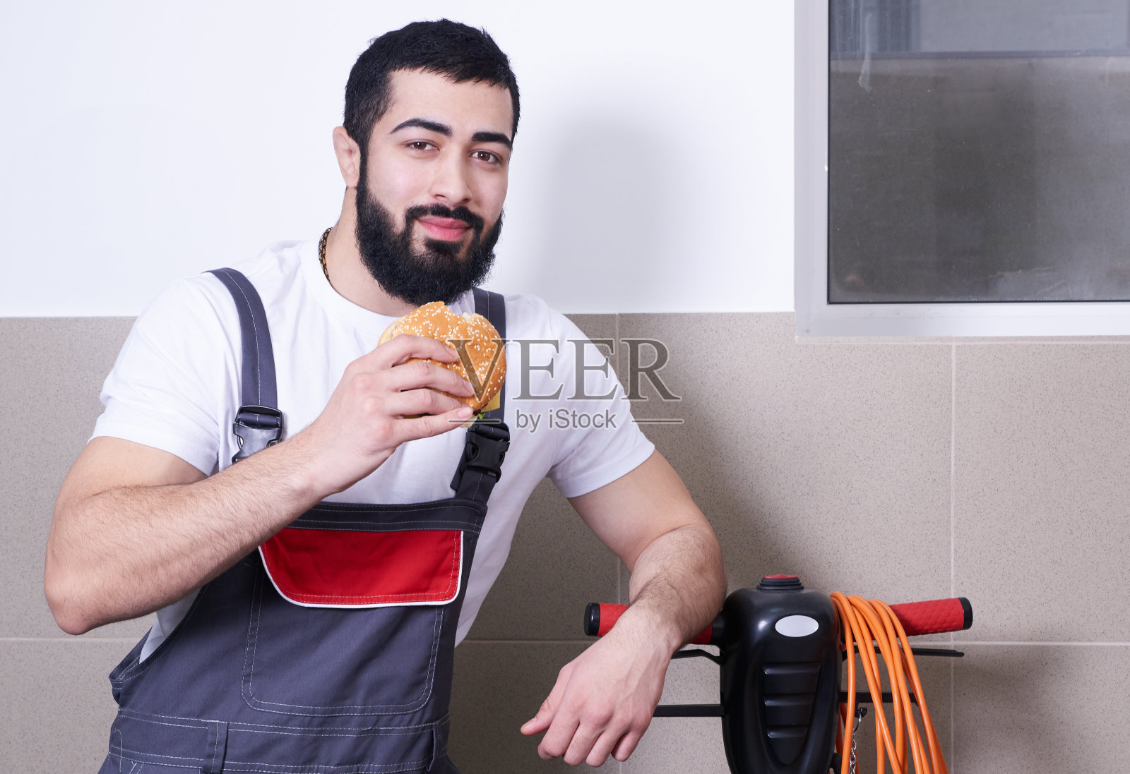 工人午休时间穿着制服吃汉堡照片摄影图片