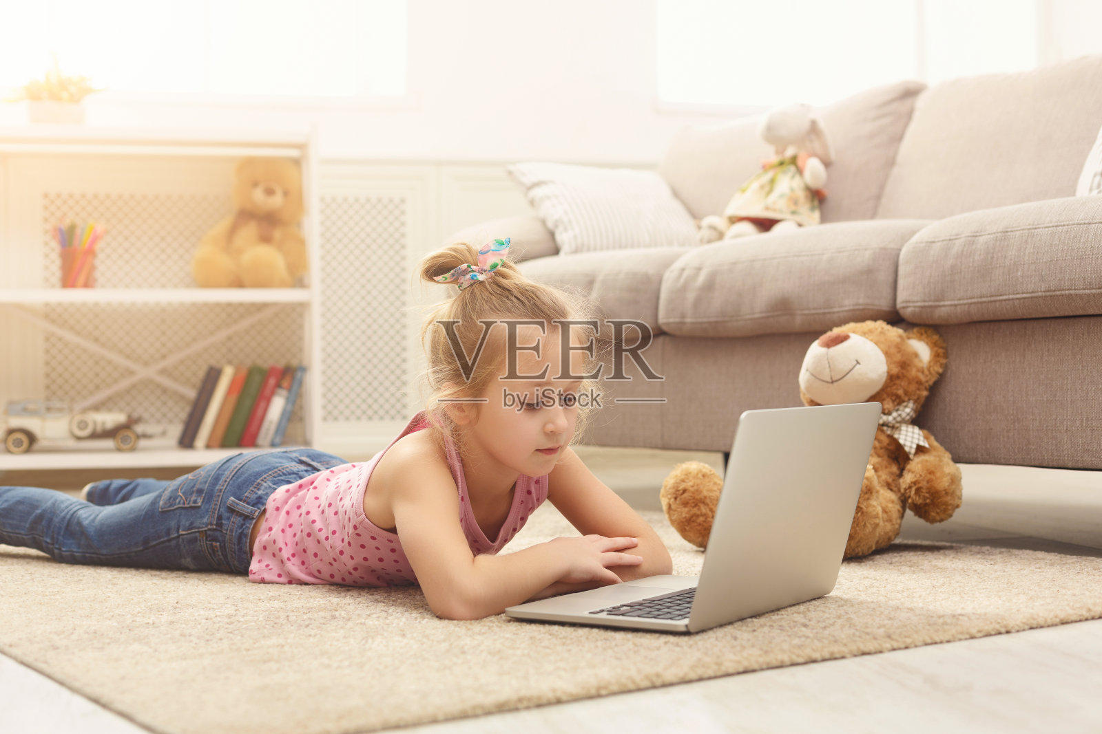 可爱的小女孩坐在家里的地板上用笔记本电脑做作业照片摄影图片