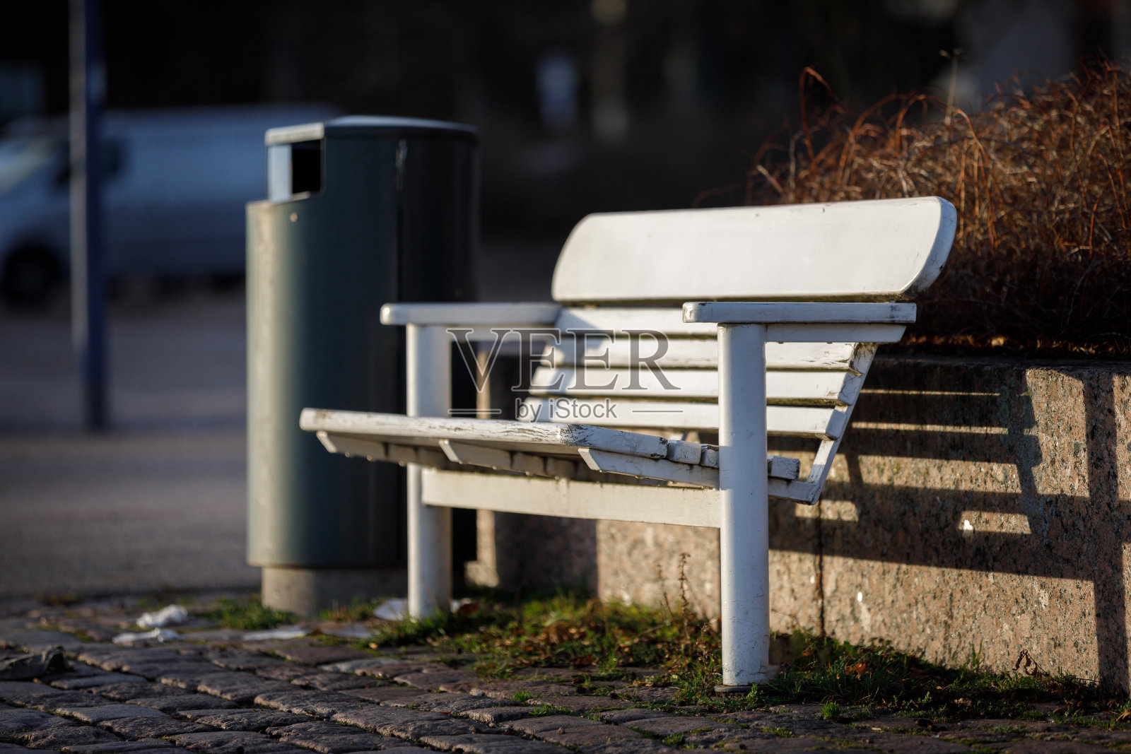 城市里的白色长凳。街道背景上的长凳，背景上有一个骨灰盒。照片摄影图片