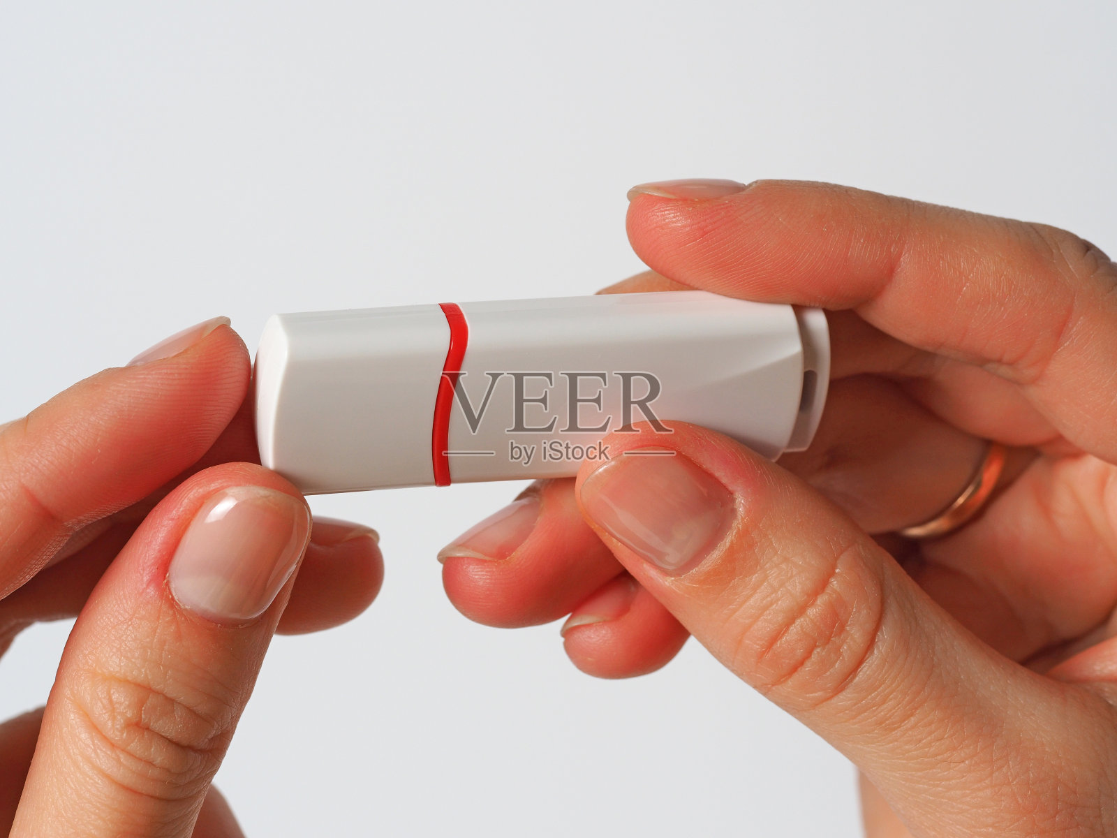 那个女孩拿着一个白色u盘。靠近，正面照片摄影图片