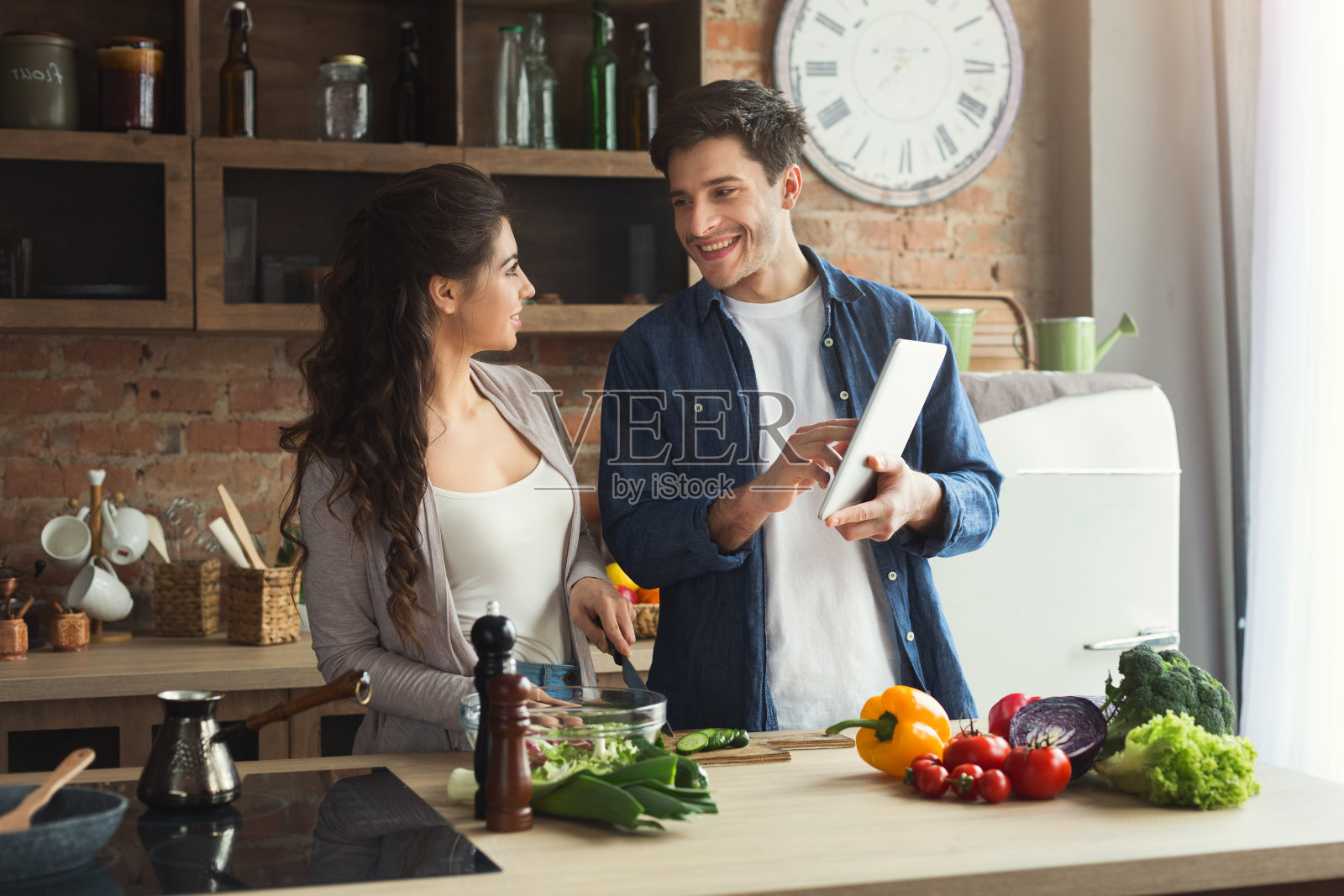 一对美丽的年轻夫妇在平板电脑上阅读食谱照片摄影图片