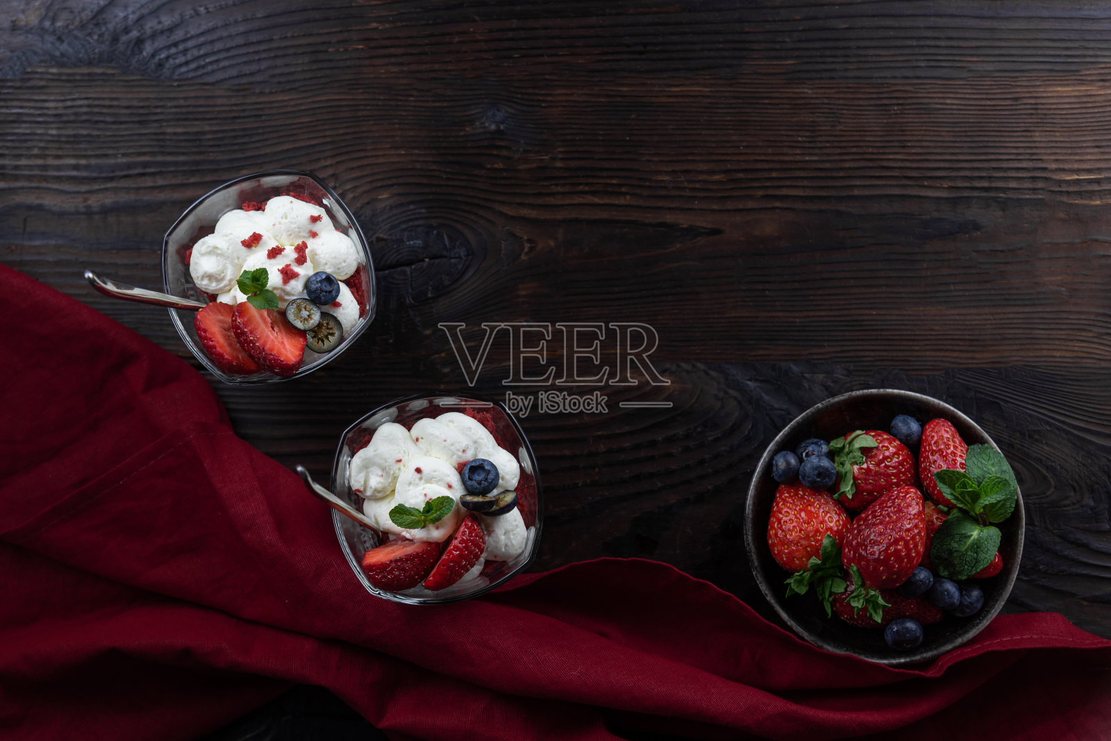 两道奶油甜点装在玻璃杯里，配上新鲜的浆果照片摄影图片