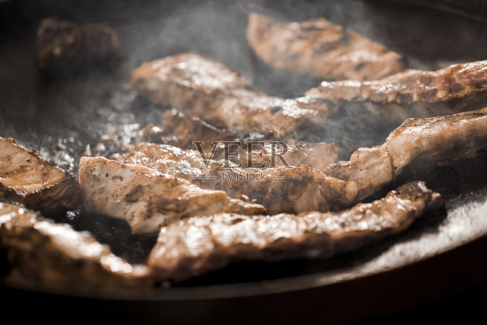 特写的烤肉在黑色背景与蒸汽网格照片摄影图片