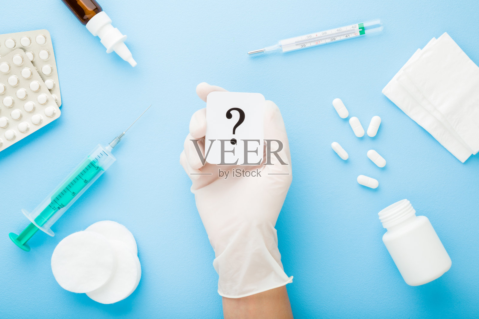 医生戴橡胶防护手套展示问号，浅蓝色桌面背景，疫情期间的不同治疗药物，医疗问题概念，俯视照片摄影图片