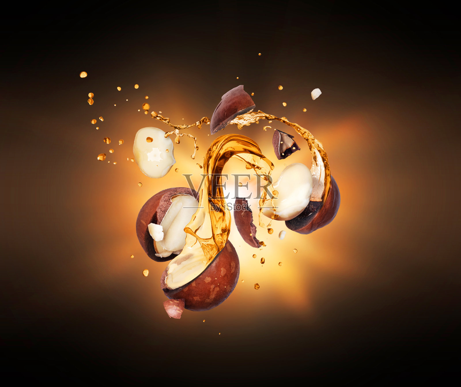 压碎的澳洲坚果与油溅在空气中，在黑暗中闪烁的光照片摄影图片