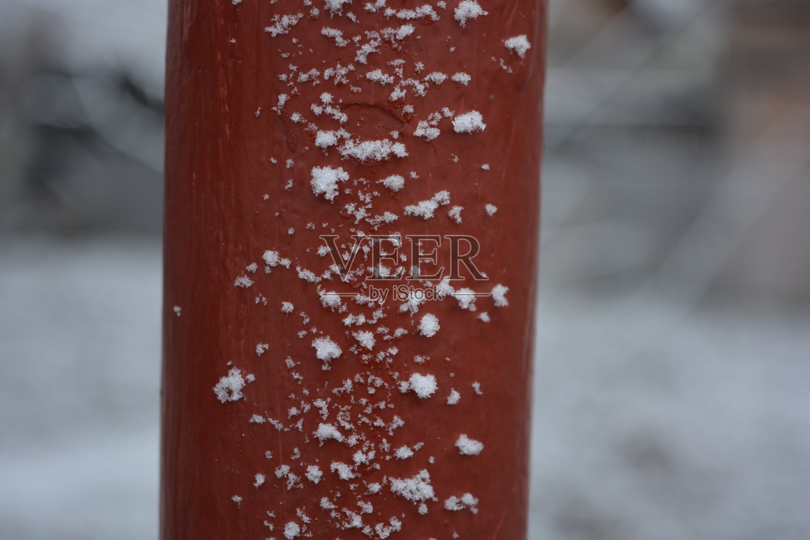 冬天下雪时，红色的金属管上覆盖着大而蓬松的雪花。照片摄影图片