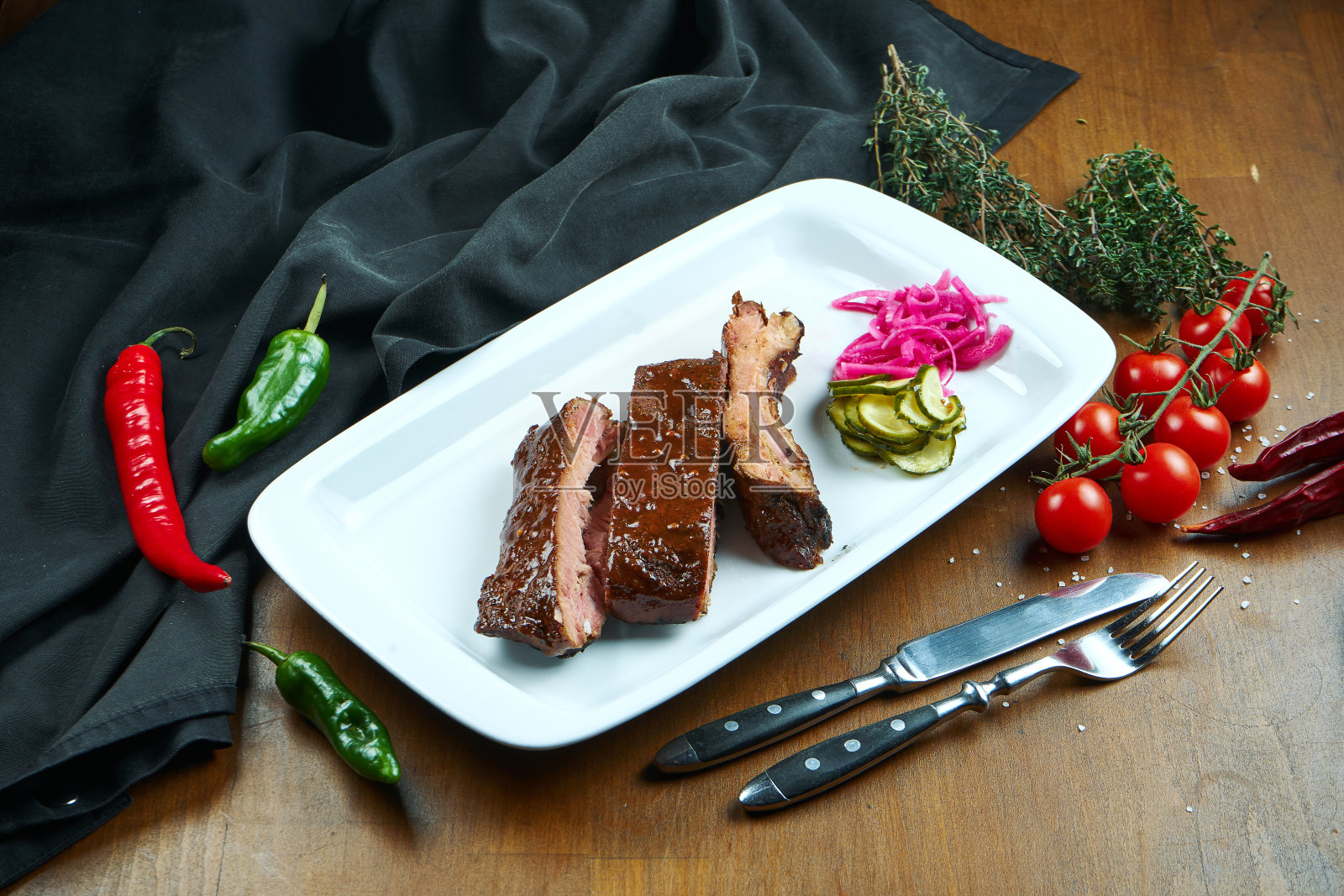 近距离观看美味的烤排骨。烧烤排骨-一个经典的美国菜肴在一个白色的盘子。木制背景照片摄影图片