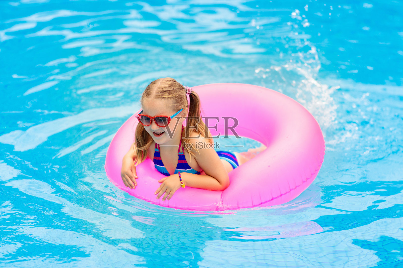 孩子在游泳池里的玩具圈上。孩子们游泳。照片摄影图片