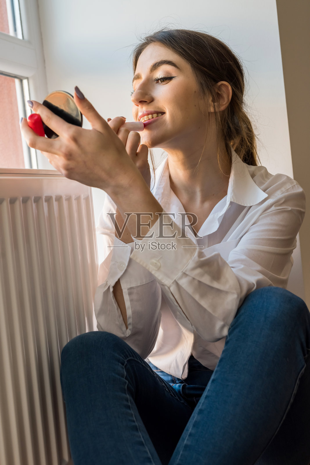 清晨，在窗边化妆的年轻漂亮女孩，美丽概念照片摄影图片