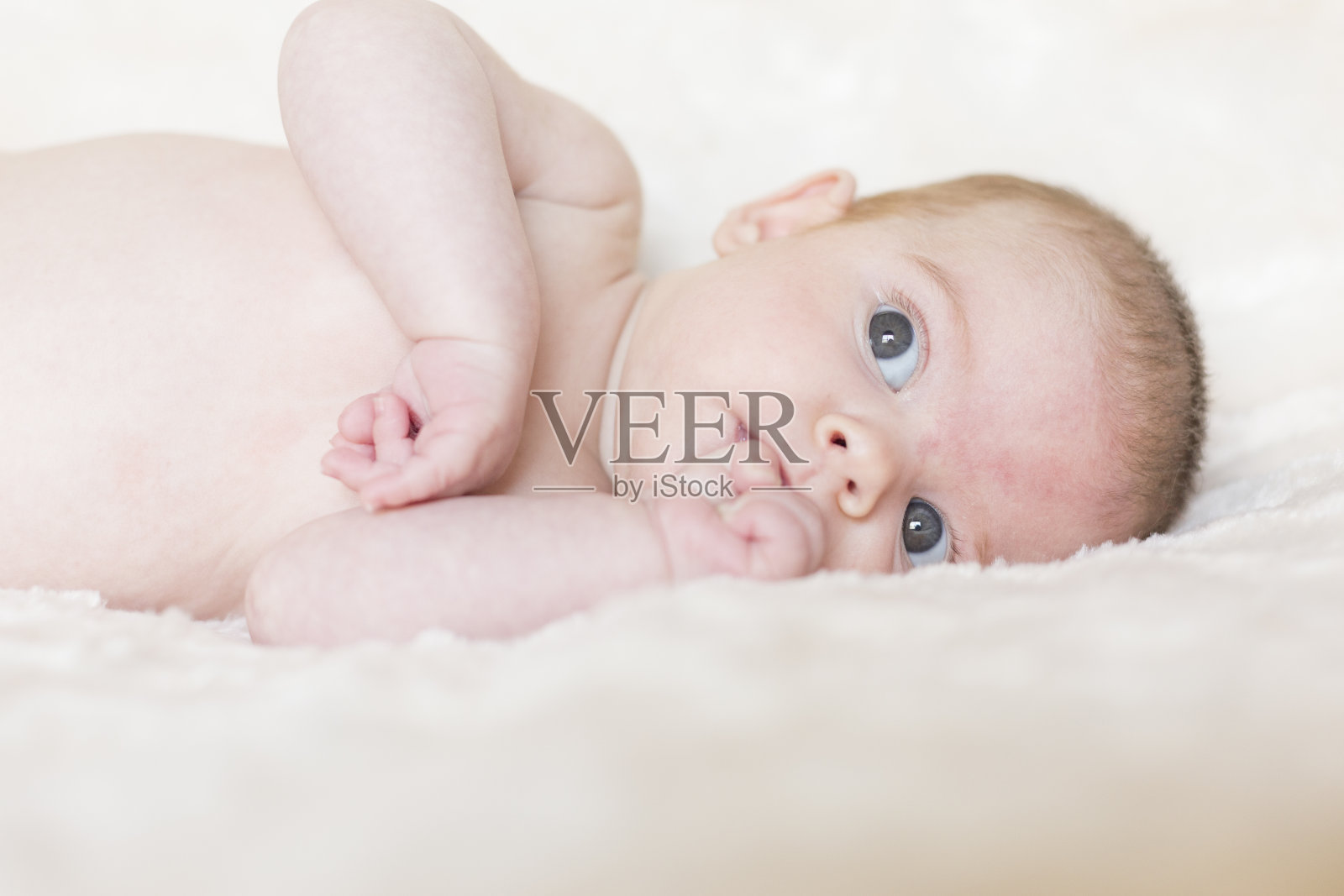 一个可爱的小女孩的肖像，醒着，看着相机。白色的毯子背景照片摄影图片