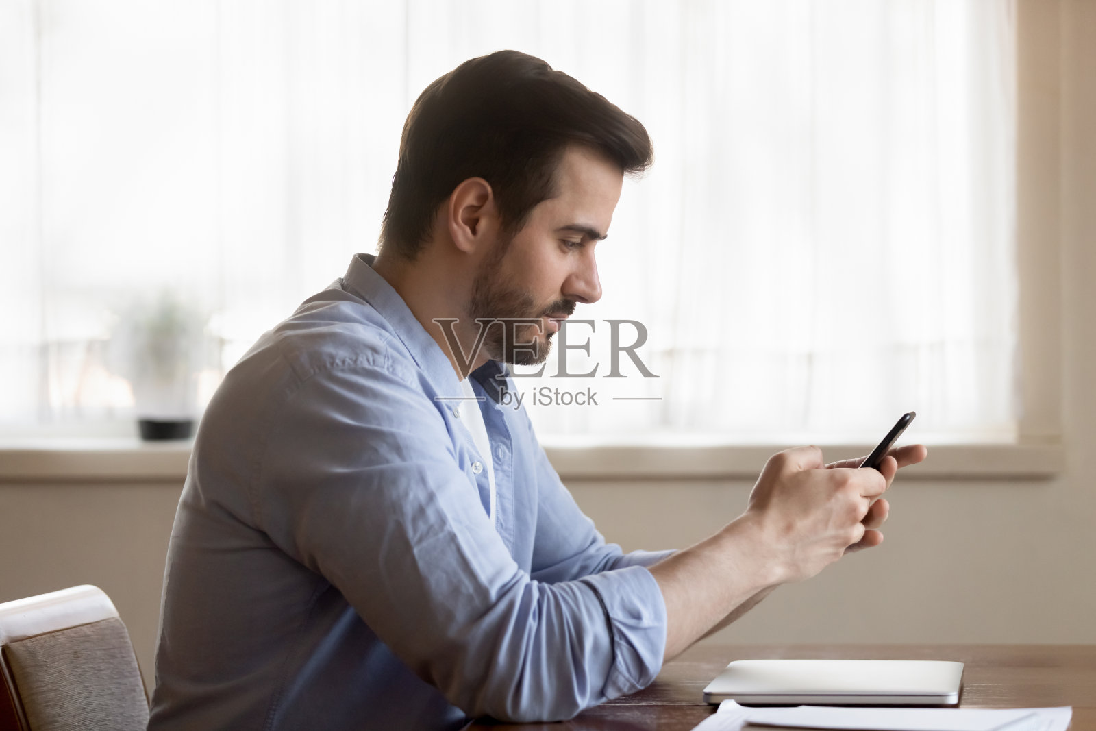 专心坐在桌旁使用智能手机的白人男子照片摄影图片