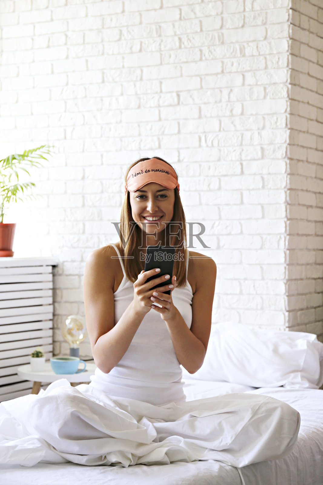 快乐的棕发女子在阳光明媚的早晨躺在床上照片摄影图片