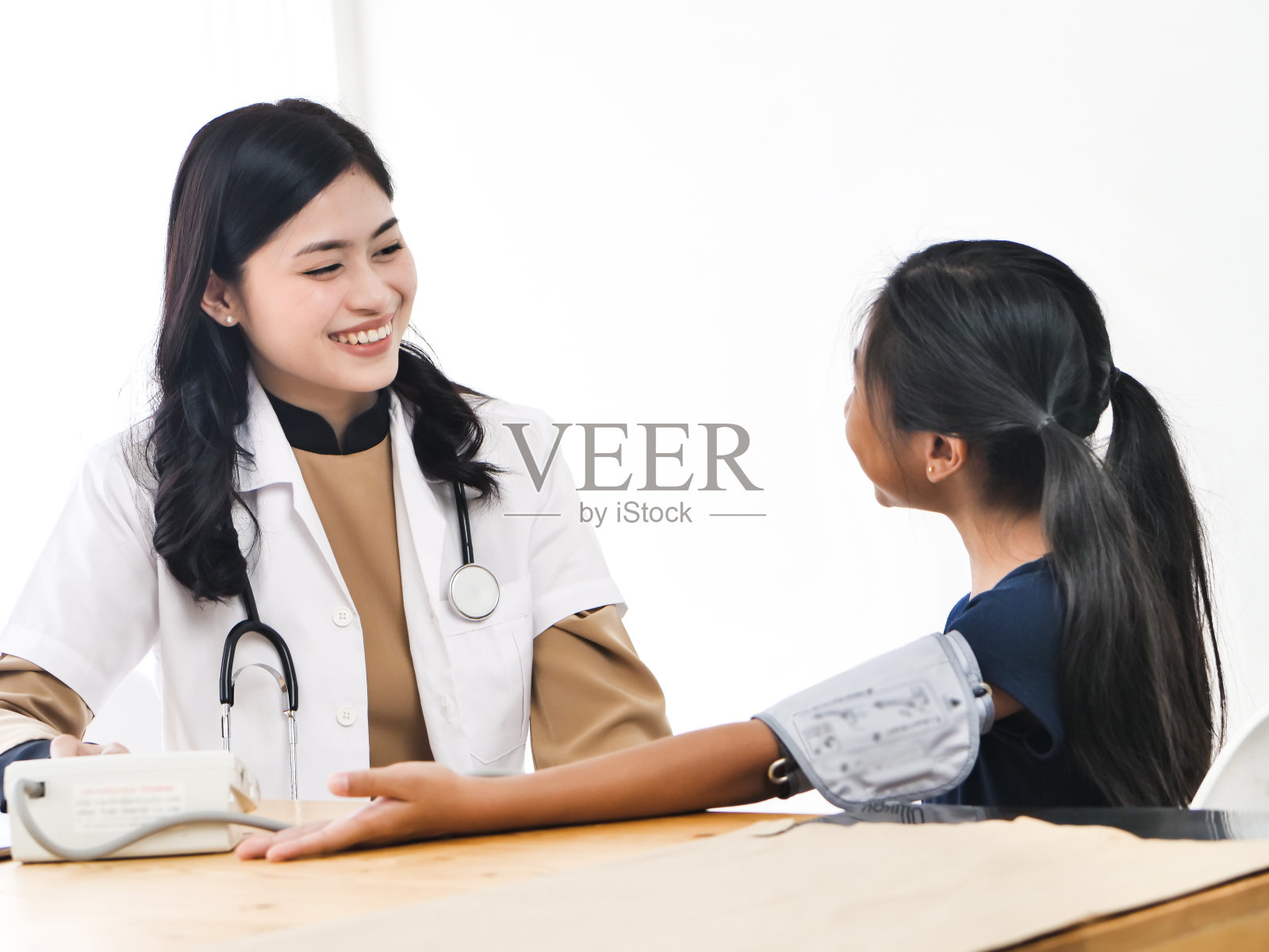 穿白大褂的亚洲女医生为儿童测量血压，护士在诊所进行检查照片摄影图片