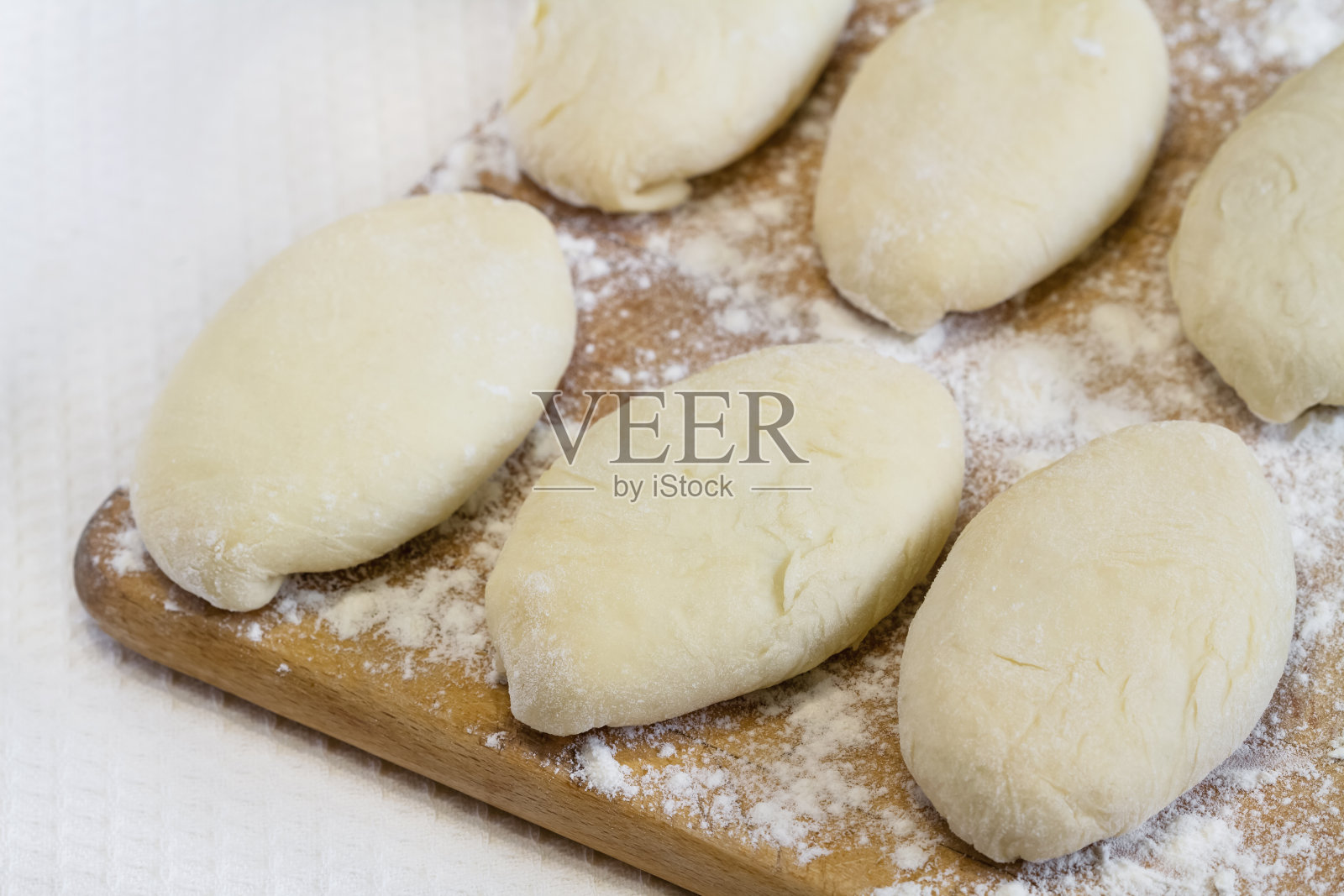 原生态自制馅饼。用酵母面团和馅料制成的未煮馅饼放在木板上，可以烘烤。特写，选择性聚焦照片摄影图片