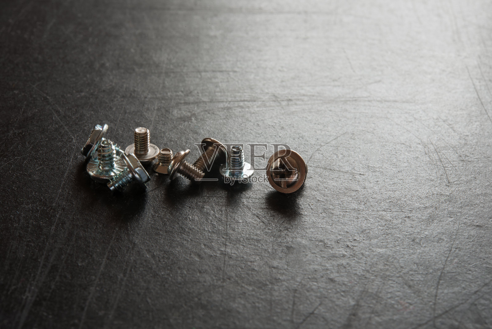 黑色背景上的一组小螺丝。照片摄影图片