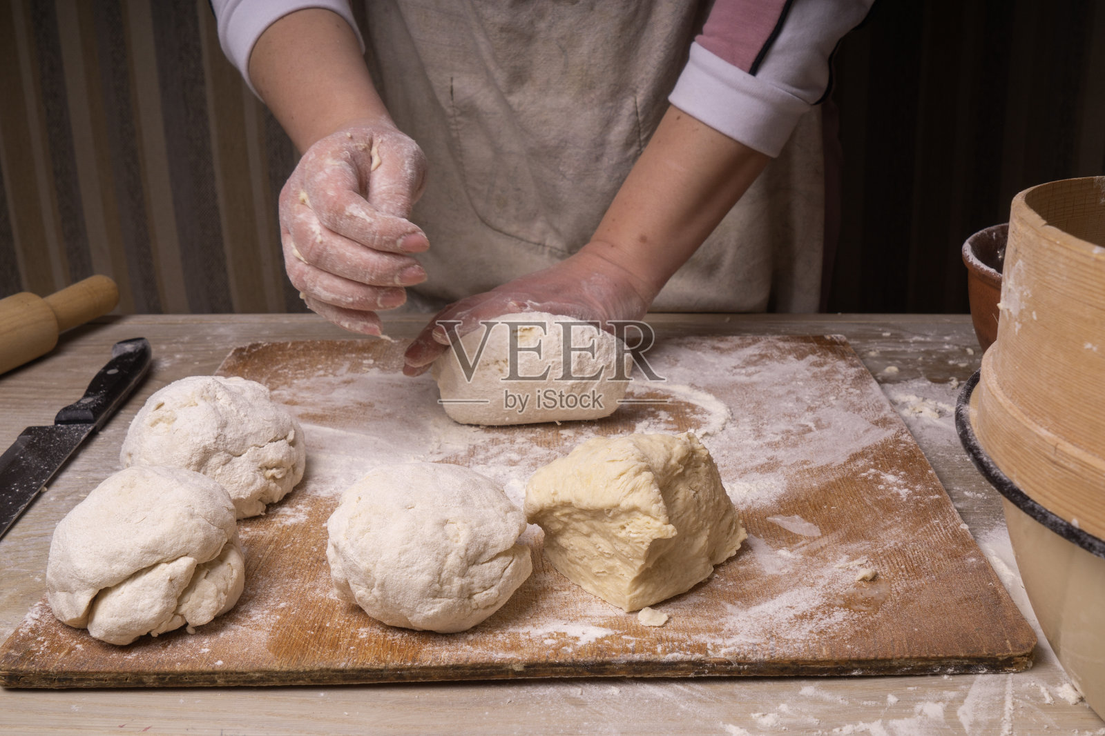 女人揉面团，胶合板砧板、木制面粉筛和木制擀面杖——制作面团的工具照片摄影图片