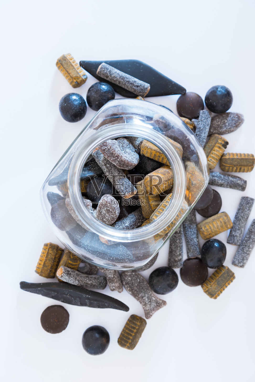 不同品种的重盐甘草在开放的玻璃罐中，在白色的背景上照片摄影图片