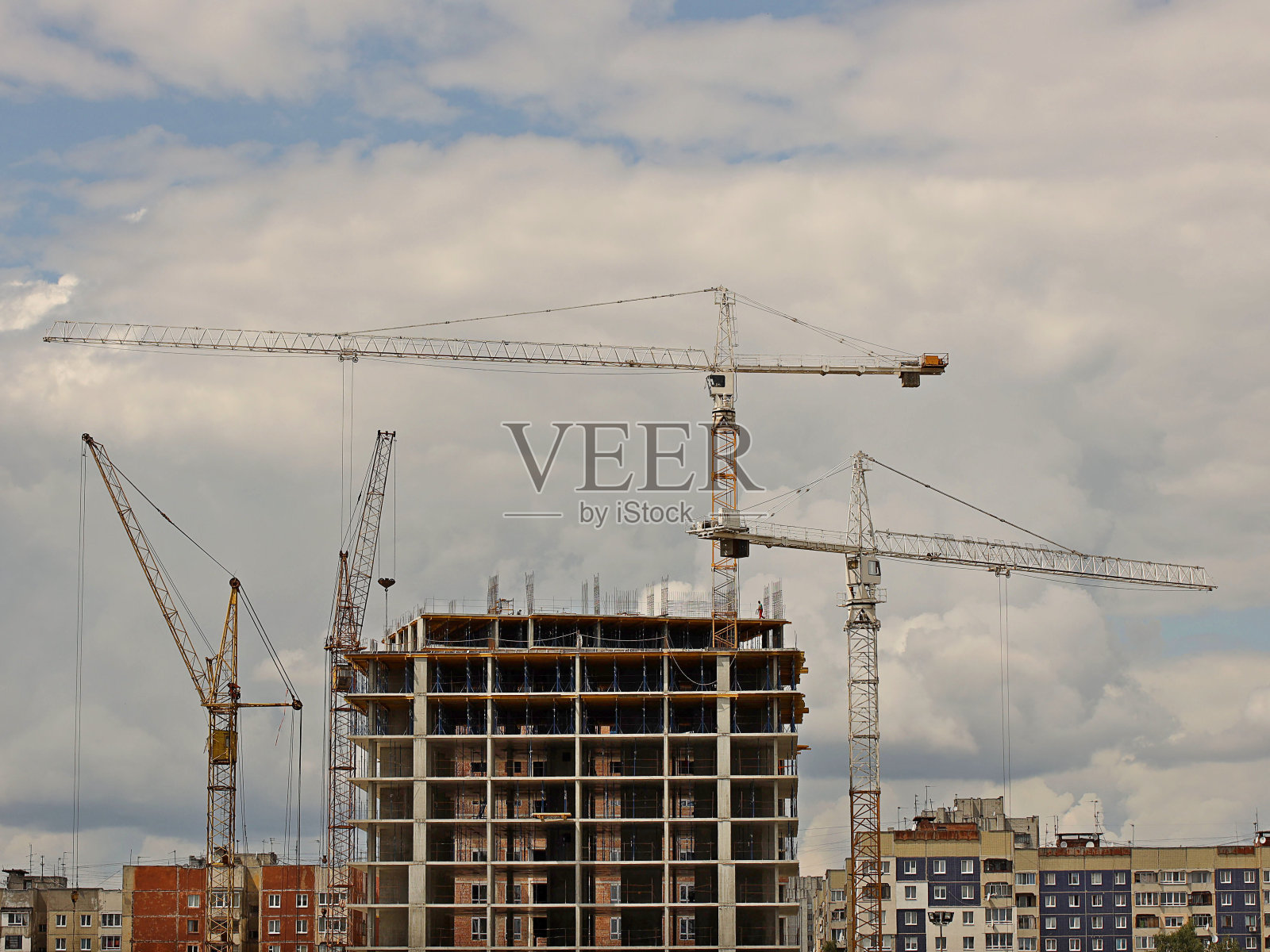 塔吊在多层建筑施工期间工作。新建居民公寓和办公楼。高空作业有风险。起重重物。城市发展照片摄影图片