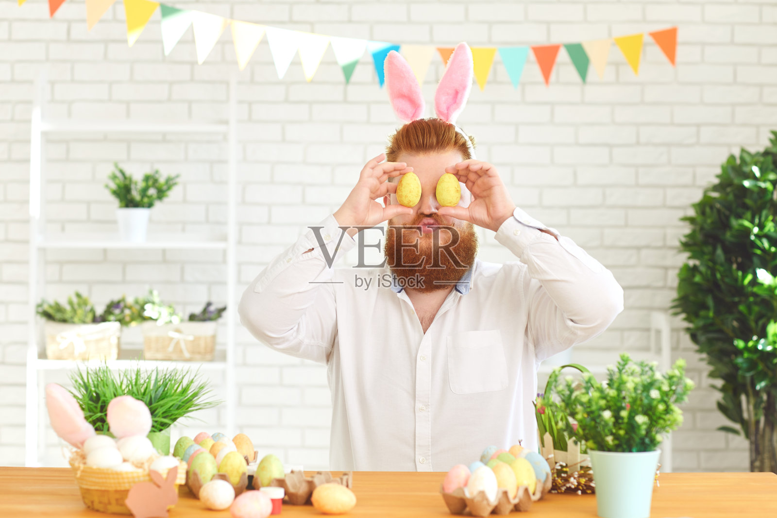 复活节快乐。一个有趣的胖男人在桌旁装饰彩蛋，背景是复活节装饰照片摄影图片