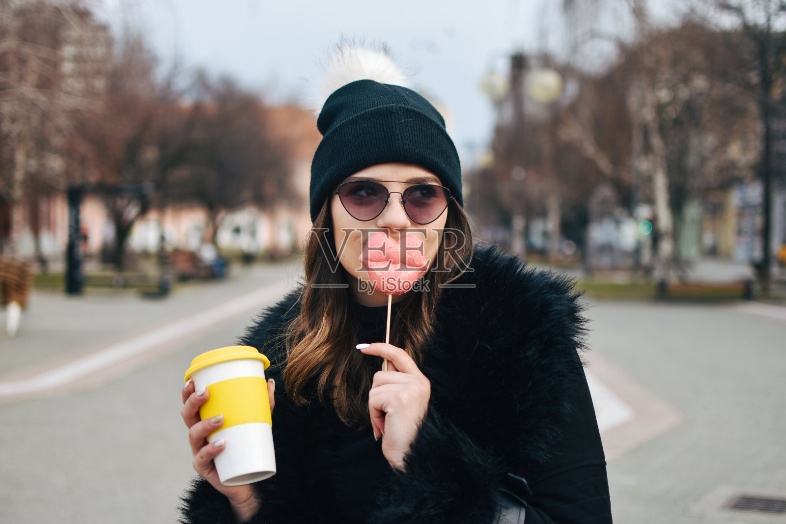 一个带着外卖饮料走在城市里的微笑女人的肖像照片摄影图片