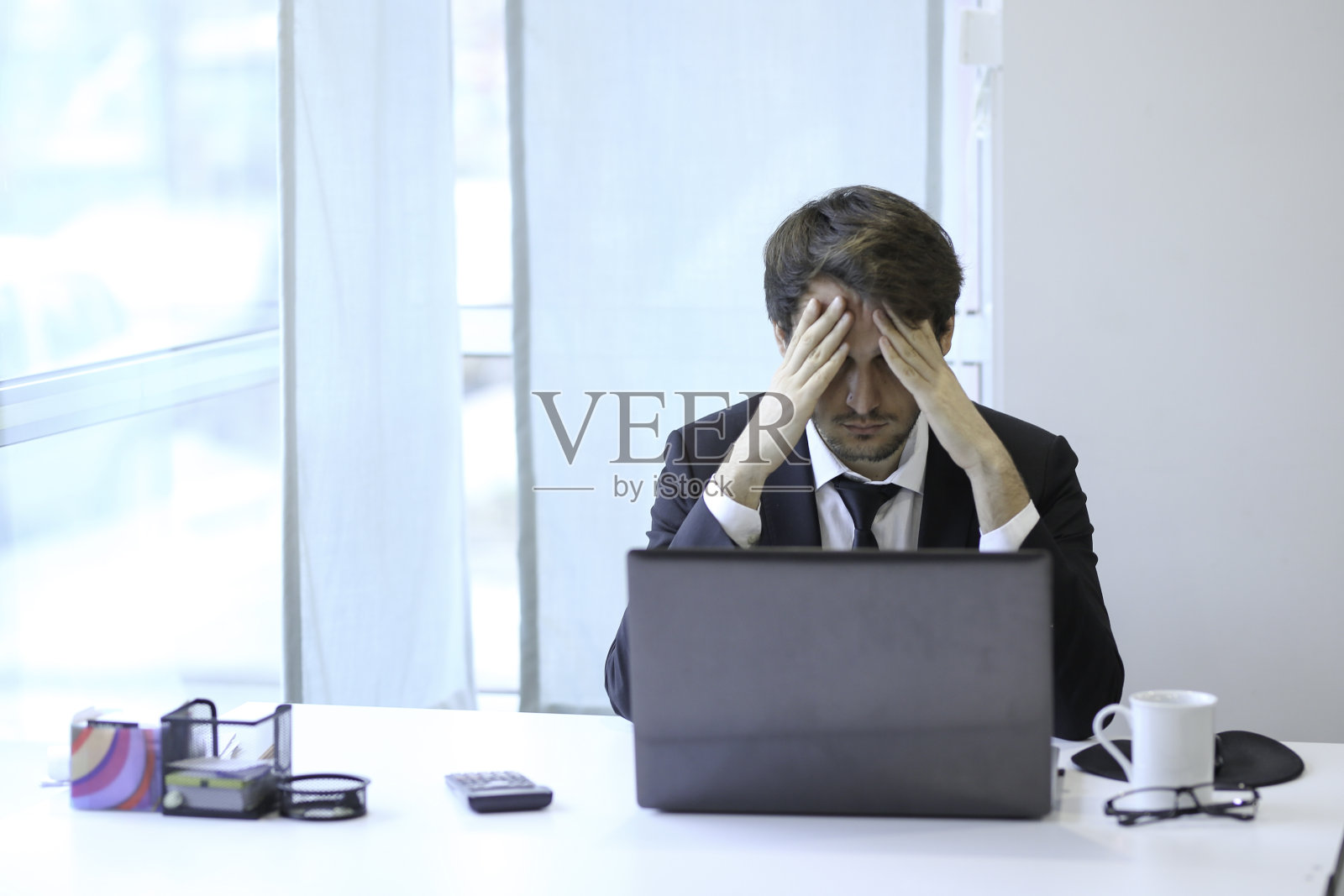 一个年轻的商人看起来压力很大，在办公室的电脑上工作到很晚照片摄影图片