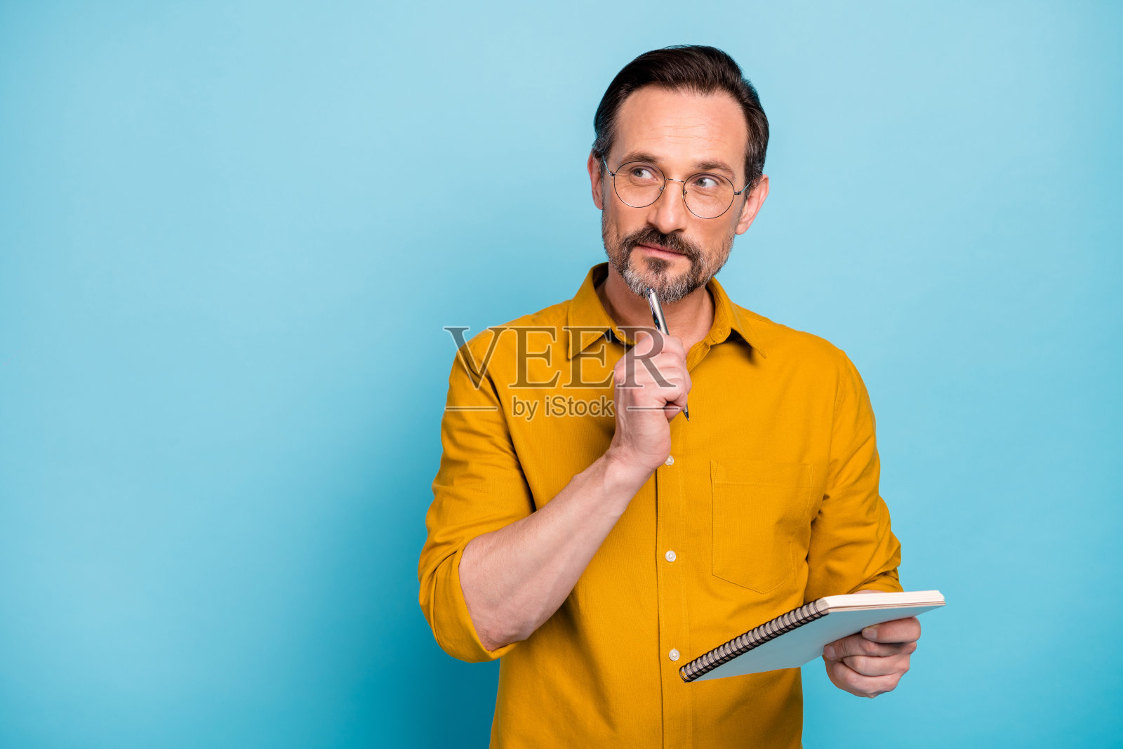 严肃专注的人的肖像，在他的抄本上写文章，思考，思考，沉思，穿现代服装孤立在蓝色的背景照片摄影图片