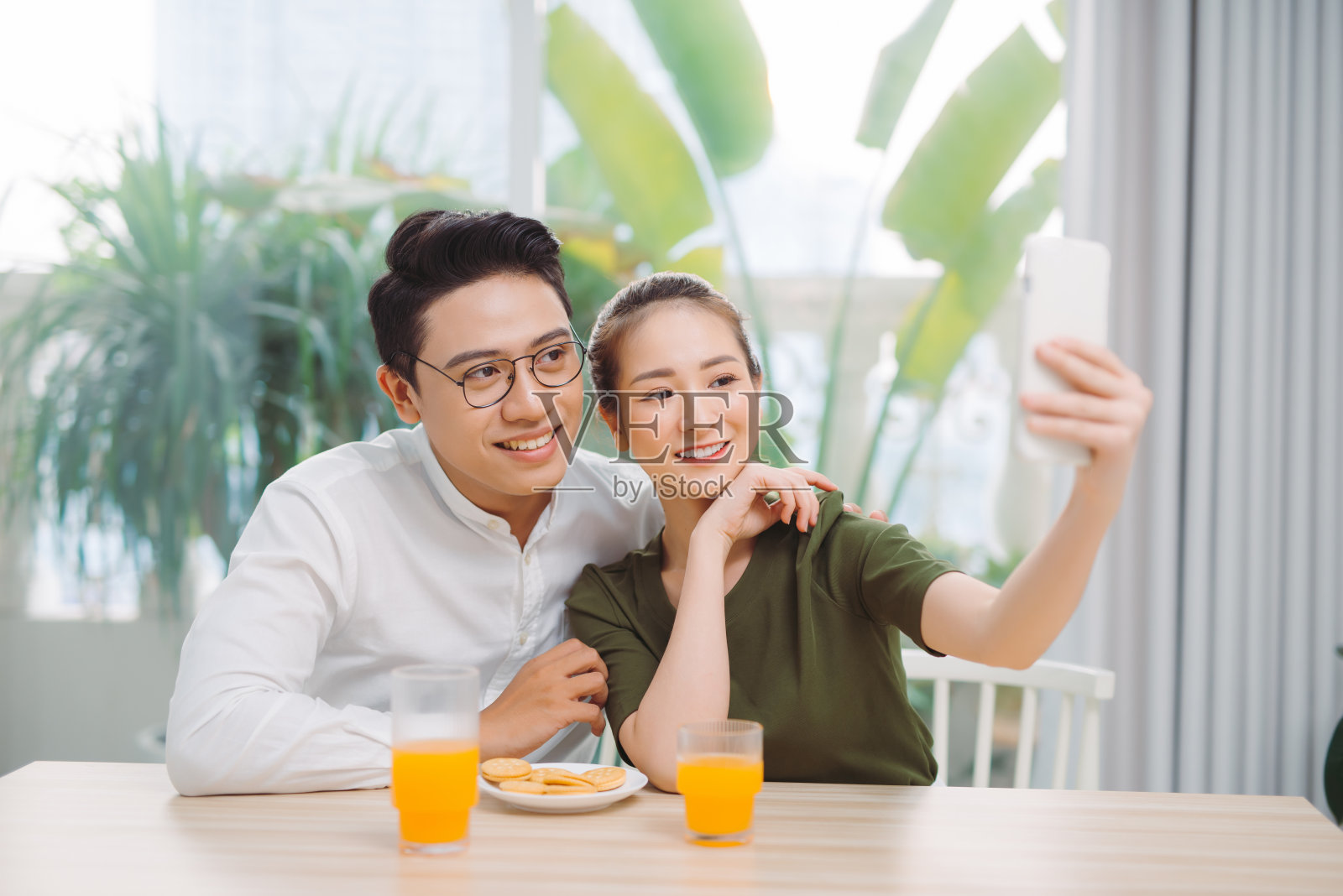 年轻情侣在公寓里自拍，使用智能手机，面带微笑照片摄影图片