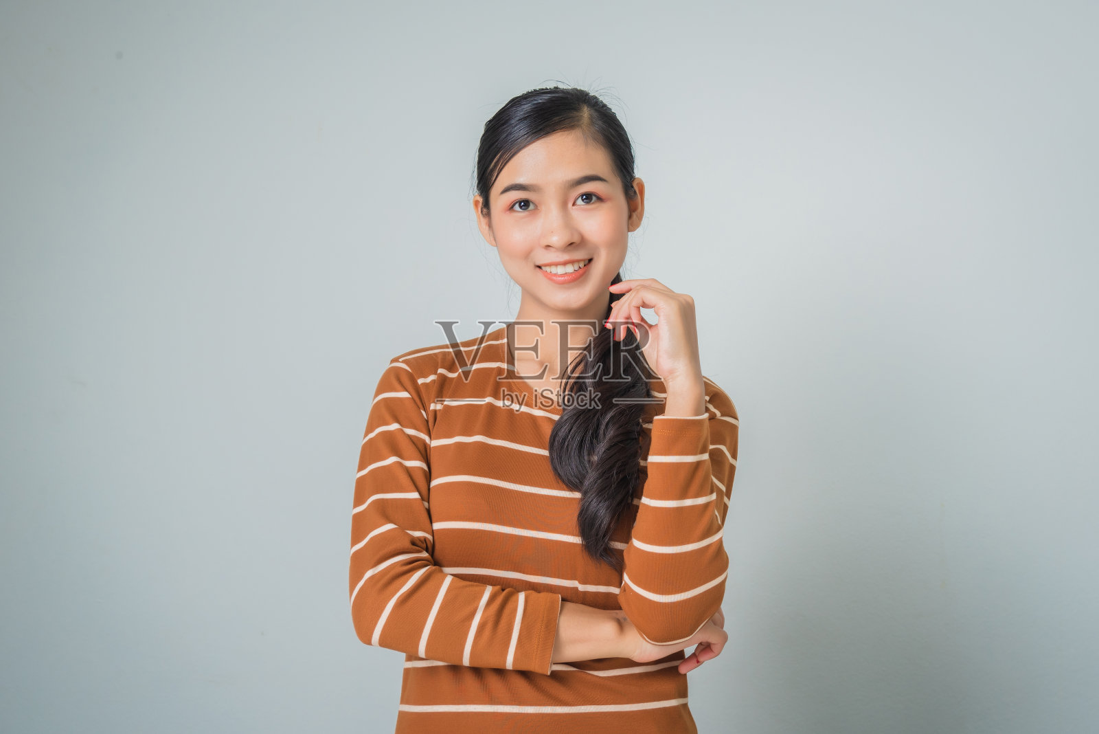 年轻的亚洲女人面带微笑，双臂交叉，穿着棕色毛衣，心情愉快照片摄影图片