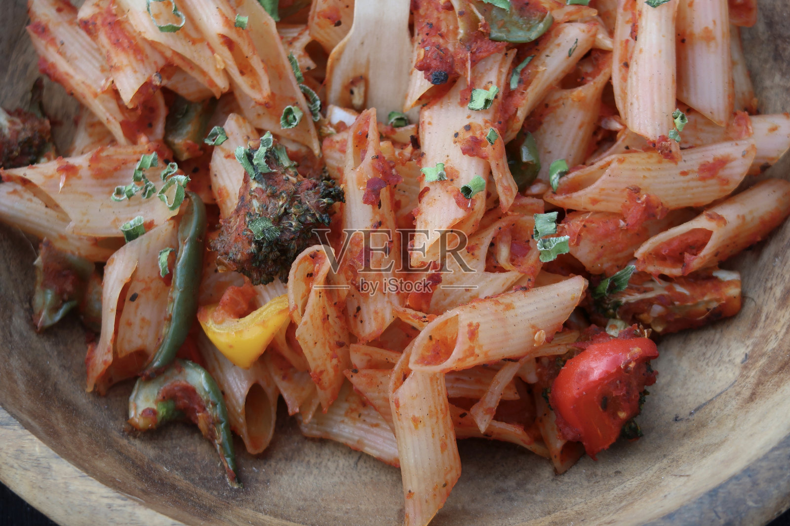 这是一碗用花椰菜、红、绿、黄三色灯笼椒配上番茄肉酱和大葱做装饰的通心粉照片摄影图片