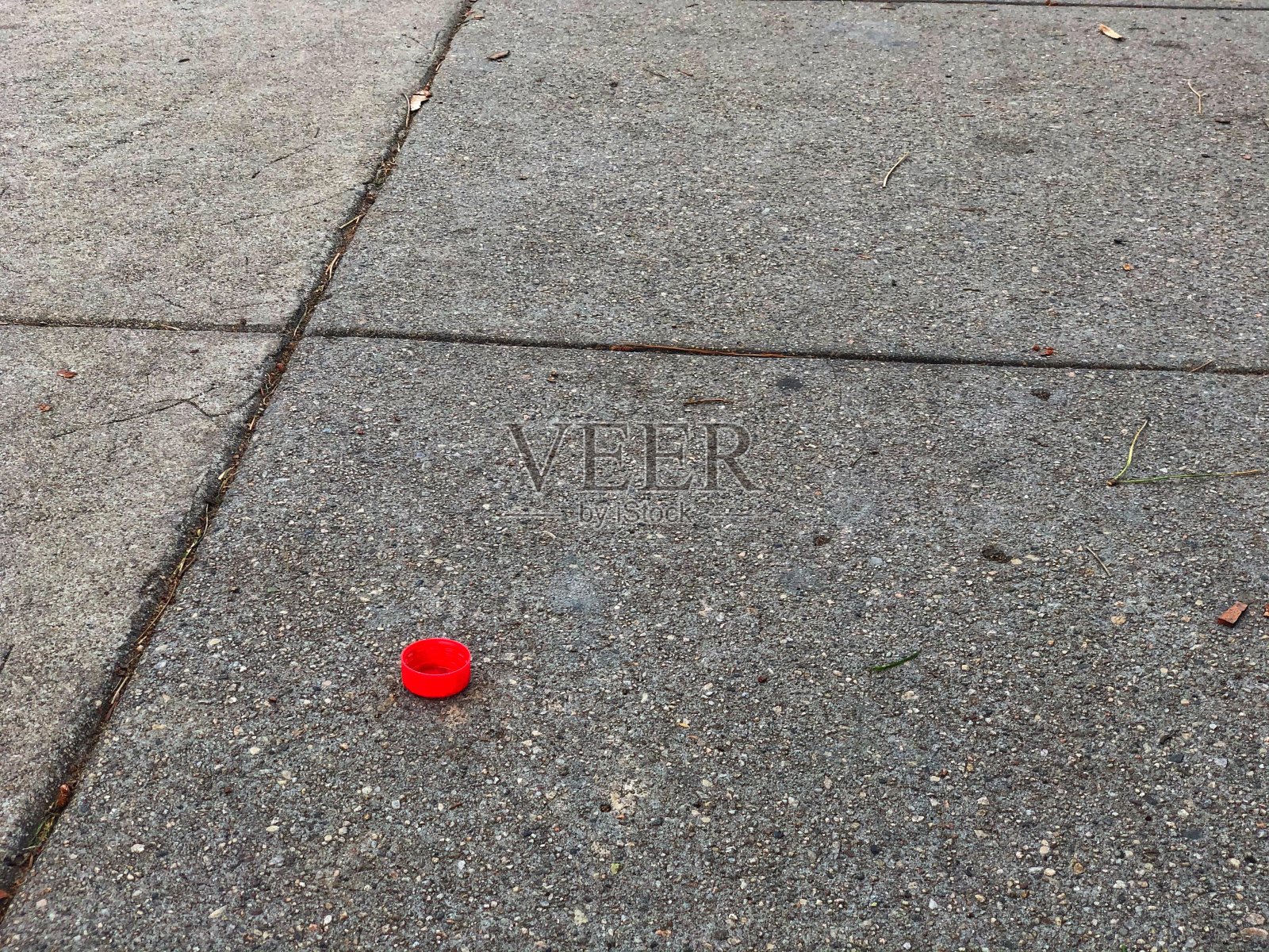 水泥人行道上的红色塑料瓶盖照片摄影图片