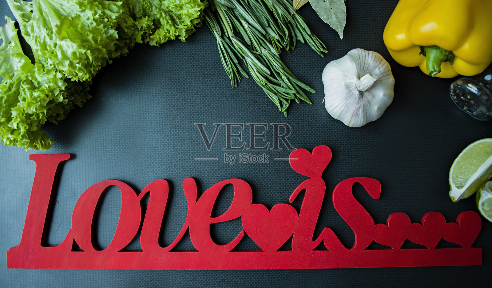深色背景上的新鲜蔬菜和绿色蔬菜。铭文“爱是…”，情人节。从以上观点。照片摄影图片
