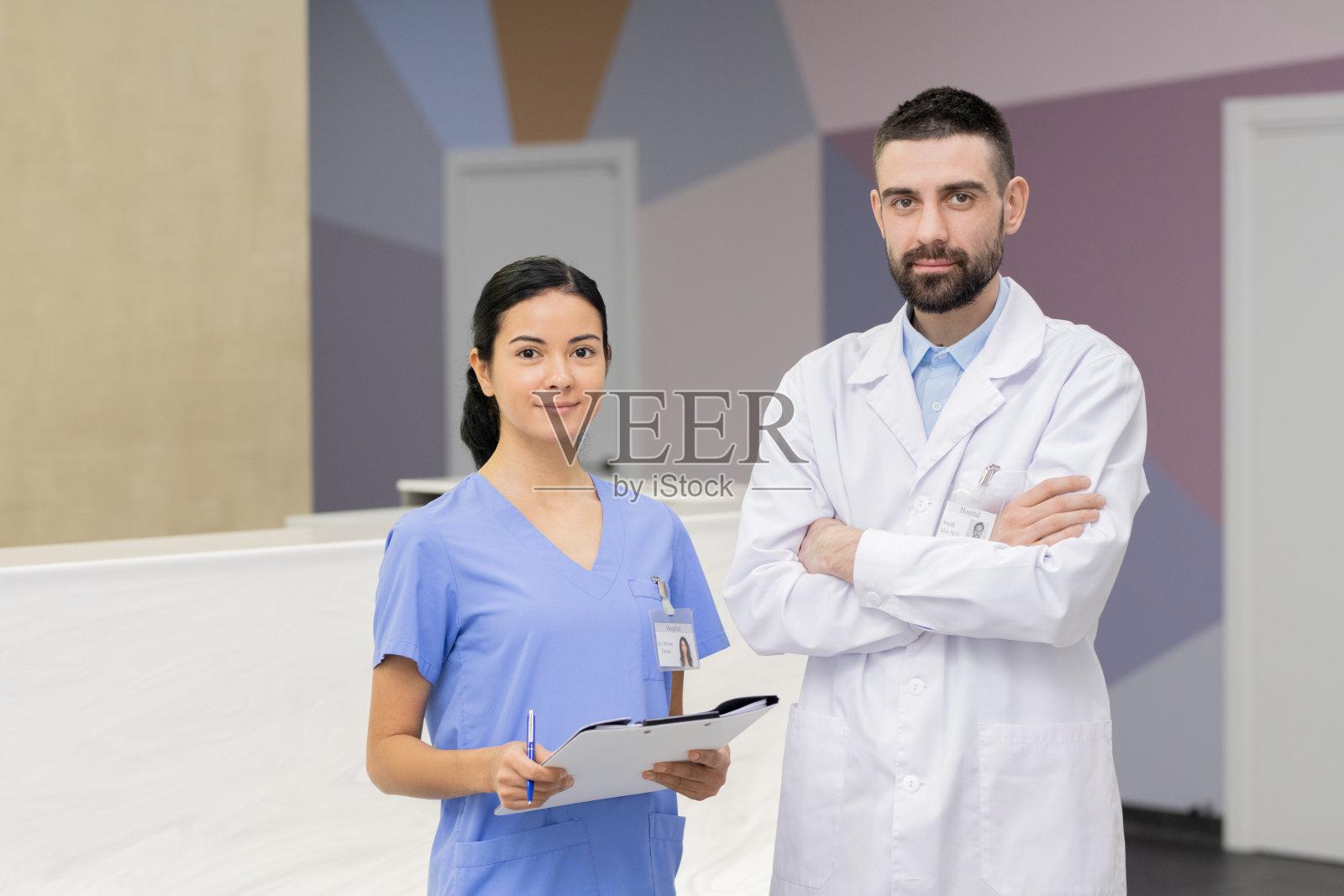 年轻自信的医生穿着白大褂和他漂亮的助手拿着文件照片摄影图片