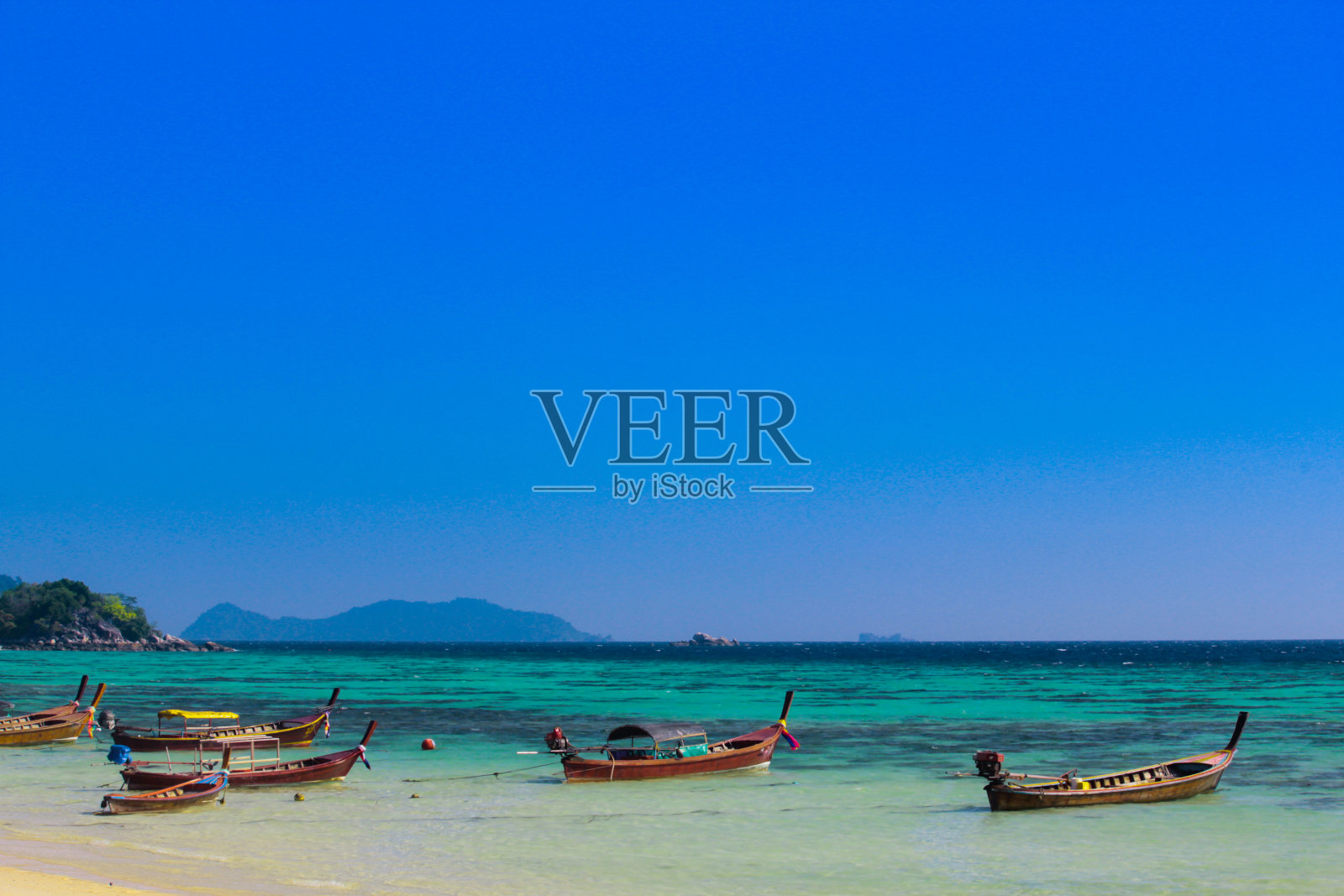 一艘渔船漂浮在泰国的Ko Lipe上。这一天，湛蓝的大海和美丽的阳光灿烂的天空。照片摄影图片