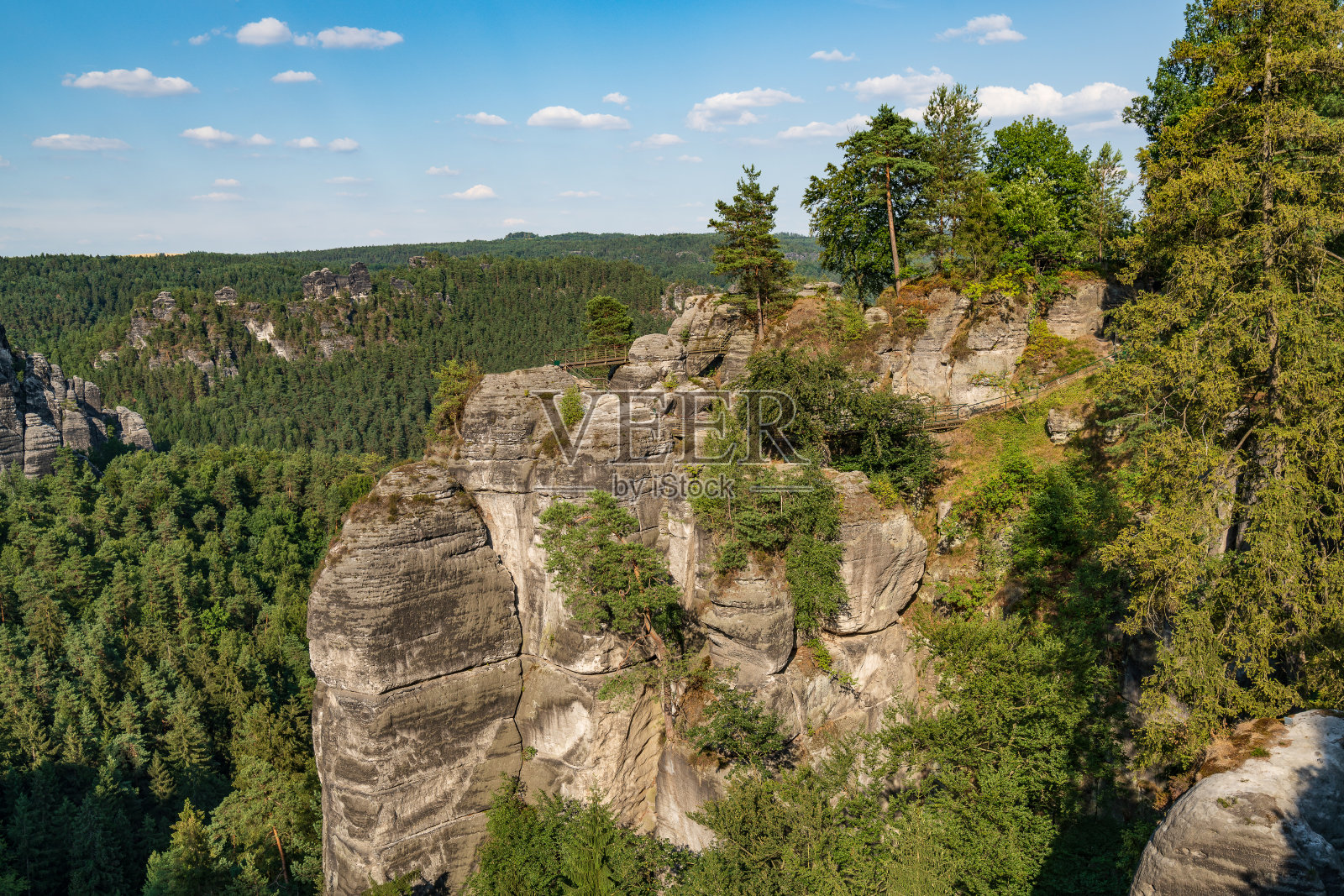 瑞士波西米亚的坏山道。巴斯蒂桥和山景。狭窄的岩石，天然的砂岩拱门在欧洲。有绿色植物、蓝天和阳光的山景。照片摄影图片