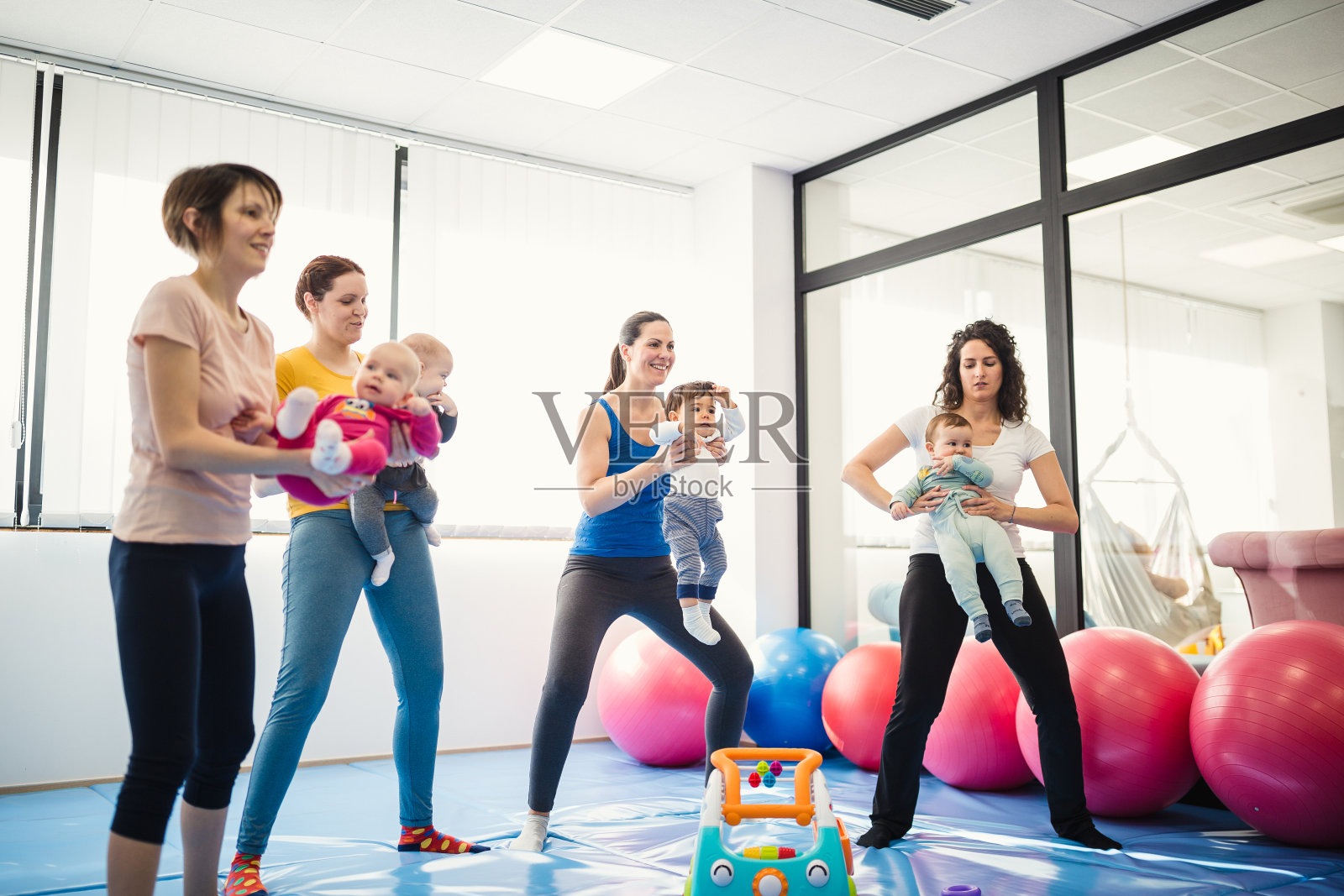 母亲和婴儿在健身班与教练照片摄影图片