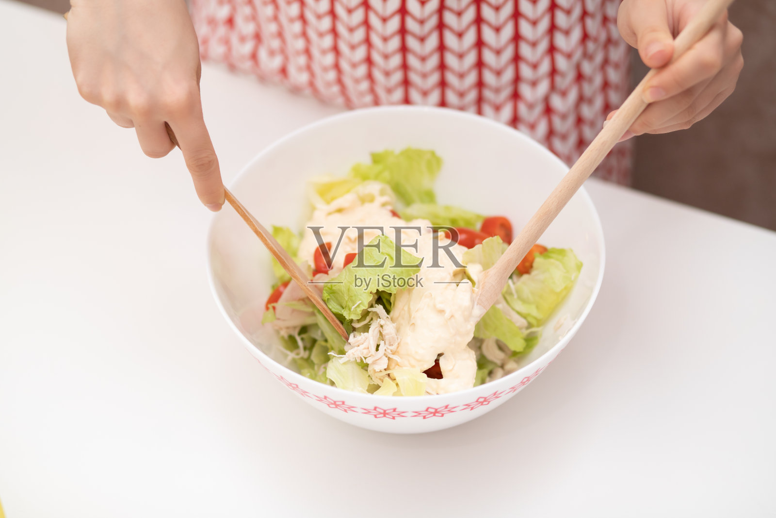 烹饪沙拉：女性之手为凯撒沙拉添加酱汁。照片摄影图片